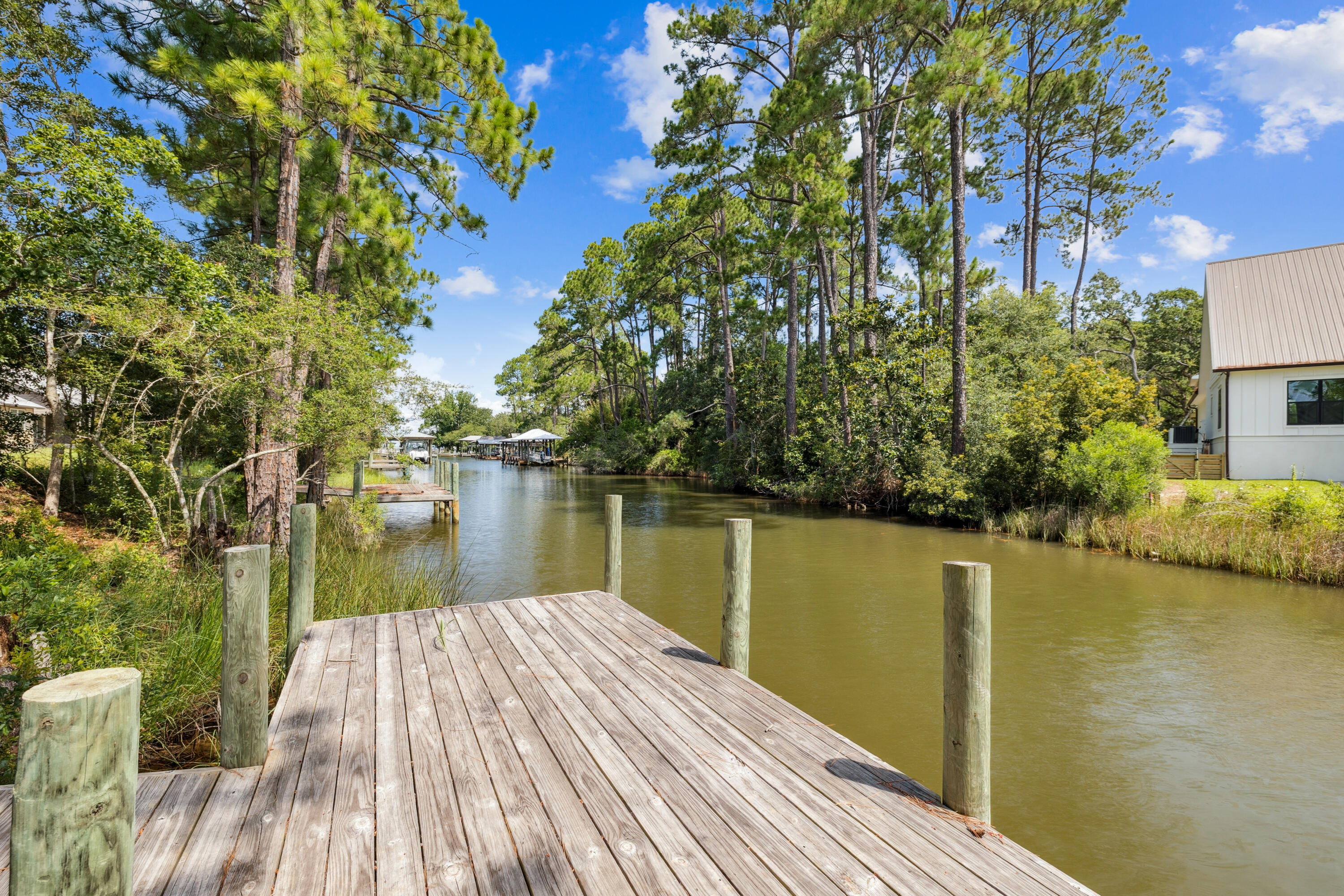 A tranquil waterfront setting and thoughtful design make this one-level Florida Cottage an inviting coastal retreat. This three-bedroom, two-bath home sits gracefully along 55 feet of serene canal frontage, complete with a private dock where you can relax with canal views or launch your paddleboard for a day on the water. Inside, the open-concept floor plan frames the canal scenery from the living, dining, and kitchen areas, complemented by soaring ceilings and recessed lighting for an airy feel. Tile floors flow throughout, blending style with easy maintenance. The kitchen features granite countertops, stainless steel appliances, generous cabinetry, and a casual elegance ideal for everyday living or entertaining. The spacious primary suite is a peaceful sanctuary, enhanced by a cathedral ceiling and tranquil water vistas. Additional highlights include nine-foot ceilings with eight-foot doors, an electric fireplace, a separate laundry room, and a two-car garage for convenience. The covered back patio invites year-round enjoyment of the coastal environment, perfectly positioned to take in serene views of the canal. With the ability to add a boat lift, this home is a rare opportunity to embrace a water-centric lifestyle, just moments from Highway 98, the pristine beaches of 30A, Grand Boulevard, and the natural beauty of Topsail Hill Preserve State Park. A perfect waterfront retreat or full-time residence where style, comfort, and location converge.