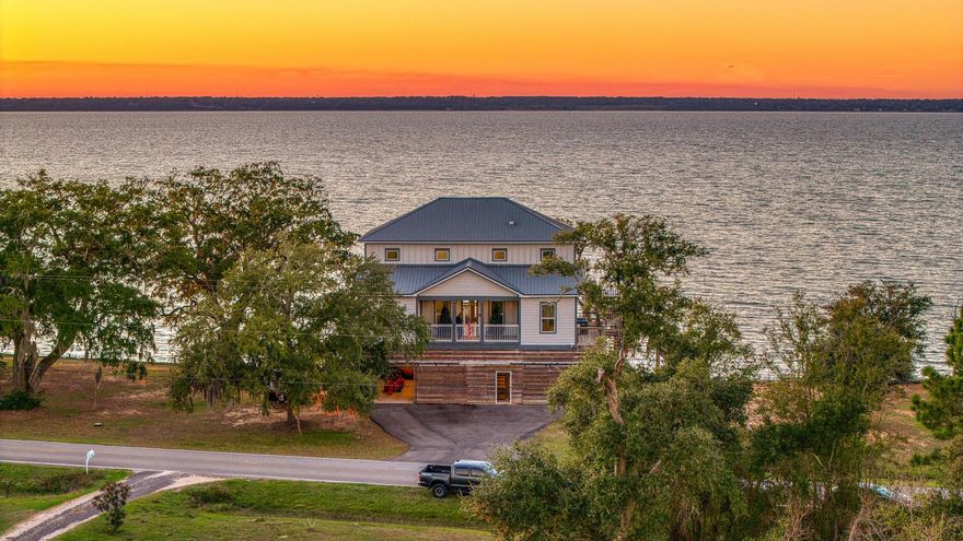 Experience coastal living at its finest in this exceptional bayfront retreat, perfectly positioned on a rare triple lot totaling .46 acres along Garcon Point Road. Offering 3 bedrooms, 2 full baths, 2,998 square feet, plus a main-floor bonus room ideal for a fourth bedroom, home office, or flex space, this thoughtfully designed home captures panoramic sunset bay views and a lifestyle centered on the water. A full-length balcony off the main floor spans the rear of the home, creating the perfect setting for outdoor dining, entertaining, or simply soaking in the ever-changing bay scenery. Upstairs, another full-length balcony accessed from both the primary suite and an additional upstairs bedroom provides front-row views of stunning sunsets and coastal breezes. Inside, abundant natural light fills the open living spaces, highlighting expansive water views throughout. The main living area features a gas fireplace and seamless flow between the living room, kitchen, and dining areas--designed for comfortable everyday living and effortless entertaining. Direct water access includes a private boat dock, seawall, and walking platform, ideal for boating, fishing, kayaking, or relaxing at the shoreline. The property also offers extensive upgrades and accessibility features, including a new driveway, elevator access to the first floor, spiral exterior staircase providing secondary egress, and a stair lift between floors. Additional amenities include an RV hookup, enclosed ground floor, refreshed rip-rap, and a full-house emergency generator powered by a dedicated 500-gallon propane tank for year-round peace of mind. Major systems have been well maintained, with the roof, HVAC system, and water heater replaced within the past five years. With rare acreage, expansive outdoor living areas, thoughtful improvements, and breathtaking bay views, this waterfront home offers an exceptional coastal lifestyle opportunity.. Book your Private Showing now !!