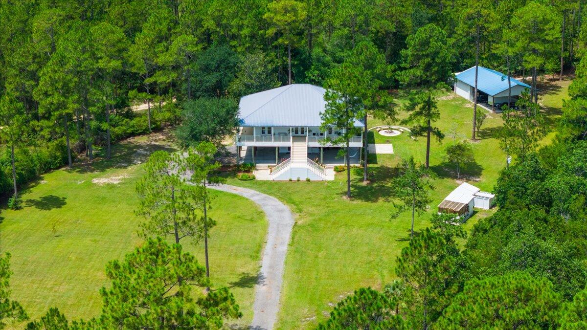 Seller offers $20k towards closing cost, prepaids or improvements at closing. Farmhouse on 5 Acres, beautifully remodeled 4BR/3BA + office retreat blends Southern charm with modern upgrades--just 17 mins to Freeport and 35 mins to 30A & PCB. Inside, enjoy fresh paint, updated baths, vaulted ceilings, and French doors from every bedroom opening to a wraparound porch. The primary suite features a private screened porch. Outside, the fully fenced 5 acres include power & water along fence perimeter, a spring-fed creek, pond, no HOA, and ample space for animals. A 1,200 lb freight elevator, powered workshop w/ garage & carport, and a new high-efficiency well add function. Plus, the concrete pad is hot tub or swim spa-ready! Flood Zone X for the home, clean landscaping.