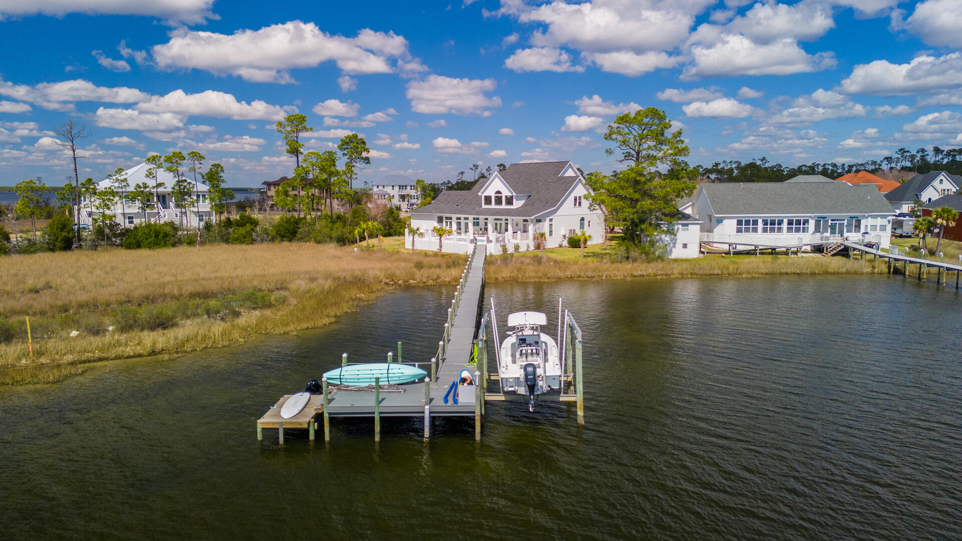 Welcome to an extraordinary waterfront estate nestled on a charming cul-de-sac, where Southern-style porches blend seamlessly with stunning Bay views. This property combines modern luxuries with transitional finishes, creating the ideal family home. On .87 acres with 120 feet of water frontage, this residence offers stunning sunsets year-round. The waterfront lifestyle is best lived outdoors and this home blends indoor and outdoor living perfectly. You'll enjoy the days in the pool and jumping in for a swim after a day on the boat. You'll love fishing from the dock and heading to Shell Island every weekend. This is the lifestyle you will enjoy year-round when you live waterfront in Northshore. You are welcomed to this gorgeous two-story home with mature oak trees that shade the large front yard. Step onto the porch and you'll see the impeccably-maintained exterior that was recently painted white to complement the coastal surroundings. This two-level home offers 4,527 square feet, 5 bedrooms, 4.5 baths, home office, 2-car garage, waterfront pool, lush landscaping and a boat dock and lift. As you enter, you'll find exceptional finishes, including hickory hardwood floors throughout, a Chef's kitchen with remarkable water views, and soaring two-story ceilings in the living room. The home office and formal dining are just off the entryway. As you walk through the two-story living room, you're greeted with a cozy fireplace, pure Bay views and direct access to the kitchen. A large island is the heart of the kitchen surrounded by a breakfast nook, casual dining area and wet bar. The kitchen boasts inset custom cabinetry, luxury stainless appliances and a stunning wood range hood. Just off the kitchen is a walk-in pantry and bar area and this leads to the garage entry and the oversized mudroom/laundry room. Stunning design finishes including gold inlay tiles, archways throughout and high ceilings make this home truly standout!
The main level is finished out with a stunning primary suite that is waterfront. As you enter this retreat, thoughtful design finishes are shown throughout including custom Schumacher grasscloth wallpaper, electric fireplace, wall sconces, hardwood floors and an ensuite primary bath only dreams are made of! This bath includes two oversized vanities-separated to maximize counter space, Quartz countertops, a tiled shower, soaking tub and two large walk-in closets. This serene retreat is truly a must see and offers a large private space within your 4,527 SF home.
This contemporary design spans onto the second level offering expansive bedrooms and 2 full baths. This level has 4 bedrooms and an expansive, impressive storage capacity - great for the holiday d??cor, sports items and so much more. One of the bedrooms hosts a large en suite bath and the other bath is a Jack and Jill bath, which has separate sink areas that can be closed off - great for children who share a bath or guests that need to share with family. All bedrooms on the upper level offer great water views and the landing between bedrooms gives great views of the Bay overlooking the two-story living area that is flooded with natural light.
As you step back into the living room and enter the outdoor living area, you'll notice the thoughtfully placed plantation shutters which open the view to the Bay but also provide a level of privacy some may desire. The covered porch by the pool is large enough for a dining table, lounge area and a hot tub. The pool is great for entertaining and with views of the Bay - you may never leave the outdoors. Step off toward the side of the house toward the garage and you'll have access to the full bath.
The best part...the dock is accessible by the pool deck and fence and offers a highly desirable composite wood decking along with a 6K LB boat lift.
Get ready to live your best life on the water in Panama City, Florida!