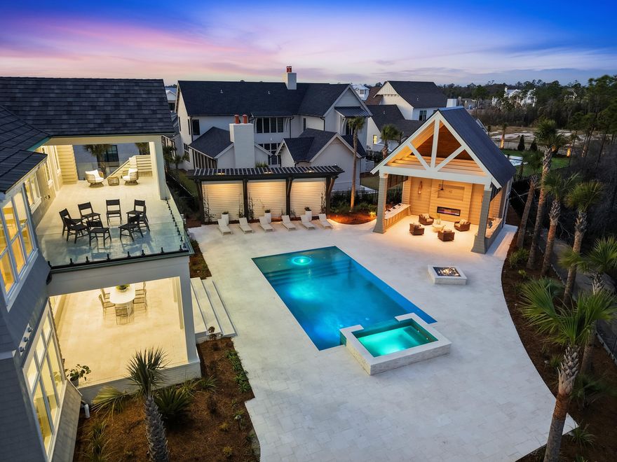 460 Golfridge Drive presents an architecturally striking coastal residence in Inlet Beach, offering more than 6,700 fully furnished square feet of conditioned living space defined by refined craftsmanship, curated materials, and thoughtfully designed indoor-outdoor living.Inside, the home's scale and natural light create an immediate sense of openness. Twelve-foot ceilings run throughout, with select spaces rising to vaulted heights of 15 to 18 feet, enhancing the airy, gallery-like atmosphere. Seven-inch engineered white oak flooring carries throughout the residence, complemented by carefully selected finishes and high-end pendant and chandelier lighting, including a remarkable Italian-made all-glass Chanel chandelier that serves as a sculptural centerpiece. The primary kitchen is thoughtfully designed as a true culinary showpiece, where refined materials meet professional-level performance. Custom white oak cabinetry and a 48-inch gas range define the space, creating an elegant yet highly functional setting for everyday living and entertaining. Just beyond, a fully equipped scullery kitchen with its own 48-inch gas range and additional refrigeration offers a rare dual-kitchen design that allows for seamless catering, preparation, and large-scale gatherings while maintaining the beauty of the main kitchen.

A dedicated wine chiller and serving station enhance the entertaining experience, while a nearby wine room with custom racks set against an oak feature wall provides a striking backdrop for displaying a curated collection. The adjoining living area is centered around a gas fireplace, bringing warmth and architectural balance to the open gathering space.

Bathrooms throughout the home reflect the same level of thoughtful design, featuring fully tiled showers and custom-crafted vanities, alongside curated John Richard furnishings and finishes that bring a tailored, design-forward aesthetic to the interiors.

Outdoor living unfolds across beautifully composed spaces designed for both relaxation and entertaining. A large sun terrace overlooks the pool, pavilion, and tranquil lake views, framed by tempered impact glass railings that maintain unobstructed sightlines. Below, the backyard becomes a private retreat with white limestone pavers, a heated pool and hot tub with sun shelf, and a custom-built gas fire pit creating a welcoming focal point for evenings outdoors.

The pool house pavilion extends the home's entertaining capabilities with a thoughtfully equipped outdoor living area featuring a 70-inch television, electric fireplace, bar refrigerator, Blaze stainless gas grill, and outdoor sink, along with a full bathroom and storage. Extensive brass Volt landscape lighting highlights the home's architecture and surrounding grounds, while a whole-home Bose sound system provides seamless audio both indoors and throughout the outdoor living spaces.

Additional architectural and design details include Decra stone-coated aluminum shake roofing, natural gas copper lanterns, a laundry chute from the second floor, and a heated and cooled three-car garage that adds flexibility and convenience.

With its generous scale, carefully curated finishes, and beautifully integrated outdoor spaces, 460 Golfridge Drive offers a sophisticated interpretation of coastal living--where architectural integrity, comfort, and elevated design come together in a setting designed to be experienced and enjoyed.
