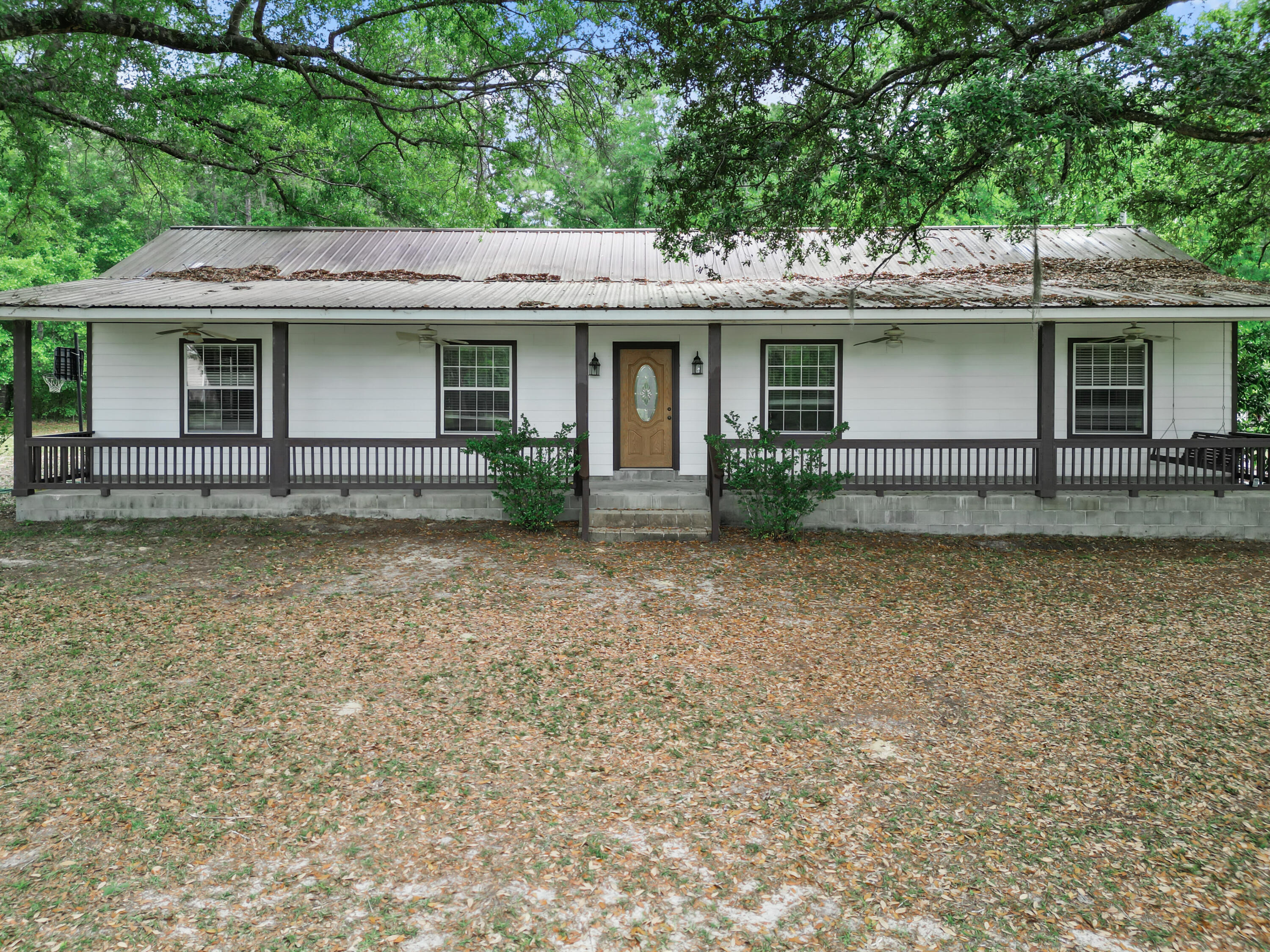 Located in the Hosford Community within Liberty County, Florida this 3-bedroom, 2-bath home is situated on 6 acres, offering a perfect blend of open space and wooded privacy. Relax and unwind on the expansive front and back covered porches, surrounded by mature oak trees and natural views. The property features a private fish pond ideal for quiet mornings or afternoon fishing, a large cooking shed perfect for outdoor gatherings, and two additional storage or workshop buildings to accommodate hobbies, projects, and equipment. Conveniently located approximately 45 minutes from Tallahassee International Airport, about one hour to downtown Tallahassee, and roughly one hour and 15 minutes to the beautiful beaches of St. George Island.