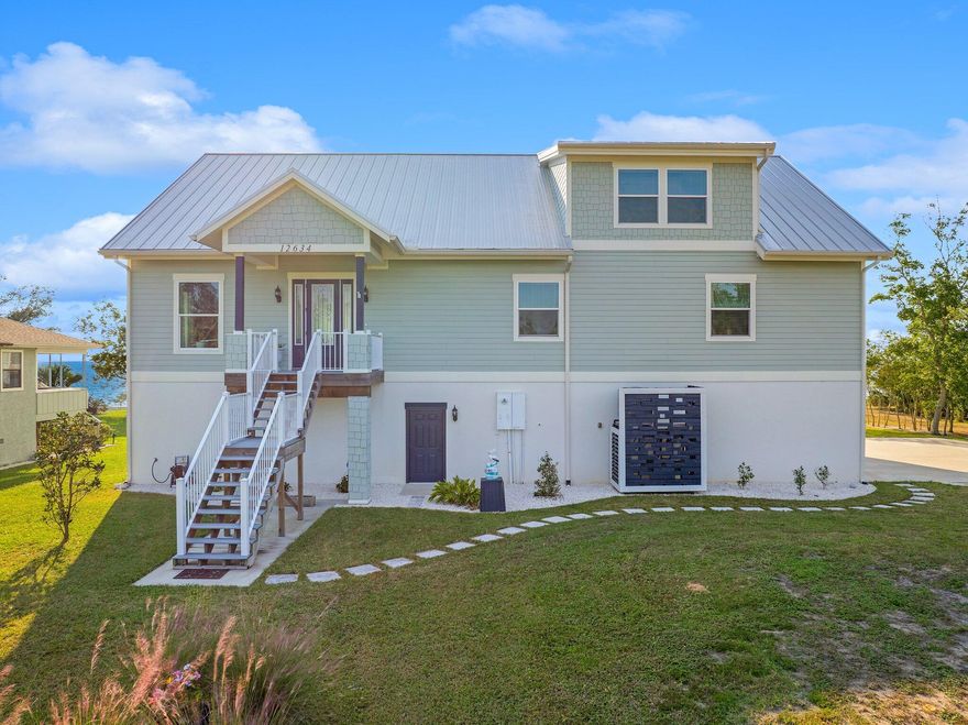 This stunning fully furnished Bayfront property offers a perfect blend of luxury, comfort, and functionality. The spacious 4-bedroom, 3-bathroom main house boasts not only breath-taking water views, creating a serene backdrop for everyday living but is built to withstand hurricanes and any other natural disaster you can think of with its ICF (Insulated Concrete Foam) Construction. ICF construction is typically rated to withstand a CAT-5 hurricane, that's a 250 mile per hour wind rating! Inside find high vaulted ceilings and 3/4'' red oak hardwood flooring flowing throughout the living spaces, with plank tile in the laundry and bathrooms and carpet in the loft area, the home exudes an open and airy feel. The kitchen is a chef's dream, featuring countertops crafted from luxurious quartz. I