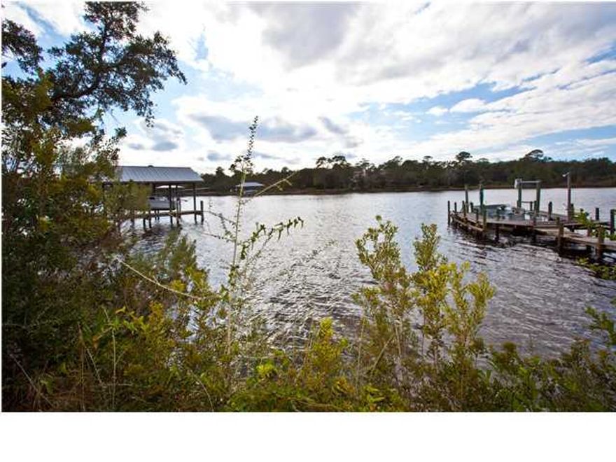 Beautiful private waterfront estate! 110 feet of deep water on Mack Bayou with over an acre of future development opportunity. This property has the potential to be transformed into town homes, single family homes or commercial space such as multifamily recreation (fish camp). Its zoning (neighborhood infill) permits the possibility of eight units per acre. This large waterfront parcel includes a cottage, mature trees with walking paths and a sandy beach with a deep water dock very close to the opening of the bay. This beautiful private estate is convenient to the gulf beaches, bay, Sacred Heart Hospital and Grand Boulevard with shopping, dining, theaters and more.