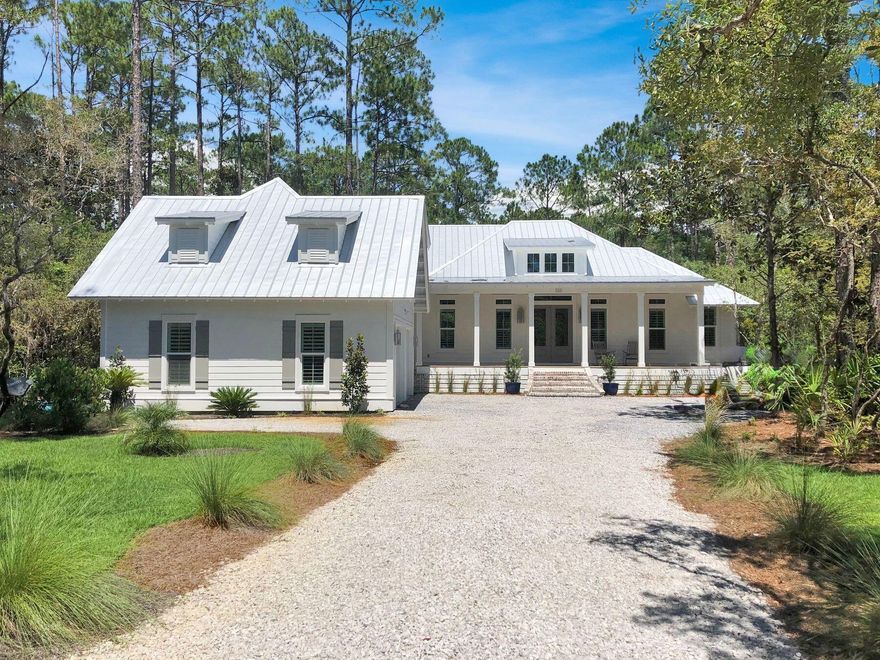 Tucked away on a private, wooded 1-acre lot in Bay Magnolia, one of Point Washington's most desirable communities, this beautifully crafted home was built in 2019 by Aqua Builders and offers upscale finishes, smart design, and peaceful surroundings. A long, winding stone driveway leads to an impressive brick staircase and expansive covered front porch. Inside, you'll discover 2,835 sq ft of heated/cooled space including 4 bedrooms and 3 and a half baths. The main living area features vaulted ceilings with decorative beams, a cozy gas fireplace with stone surround, and stylish wood-look tile flooring throughout. The heart of the home is a spacious kitchen with white shaker cabinets, a gas range, and generous counter space including a large island. A dry bar with beverage cooler and glass cabinet doors adds added convenience and storage. The primary suite is located on the main floor, complete with oversized windows that frame forest views. The en suite bath flows into a walk-in closet with direct access to the laundry room, which is also accessible from the hallway. Two additional bedrooms share a Jack-and-Jill bath, while a private upstairs suite offers a fourth bedroom and full bath, ideal for guests or a home office. Enjoy relaxing evenings on the covered and screened back porch, overlooking the fenced backyard. Additionally there's a 2-car attached garage. This home benefits from being located adjacent to the walking path to the bayfront park and community pier, all just minutes from the best of 30A, Grayton Beach, and Seaside. This is a rare opportunity to own a thoughtfully designed custom home in a peaceful, well-loved community within a few minutes of world class beaches.