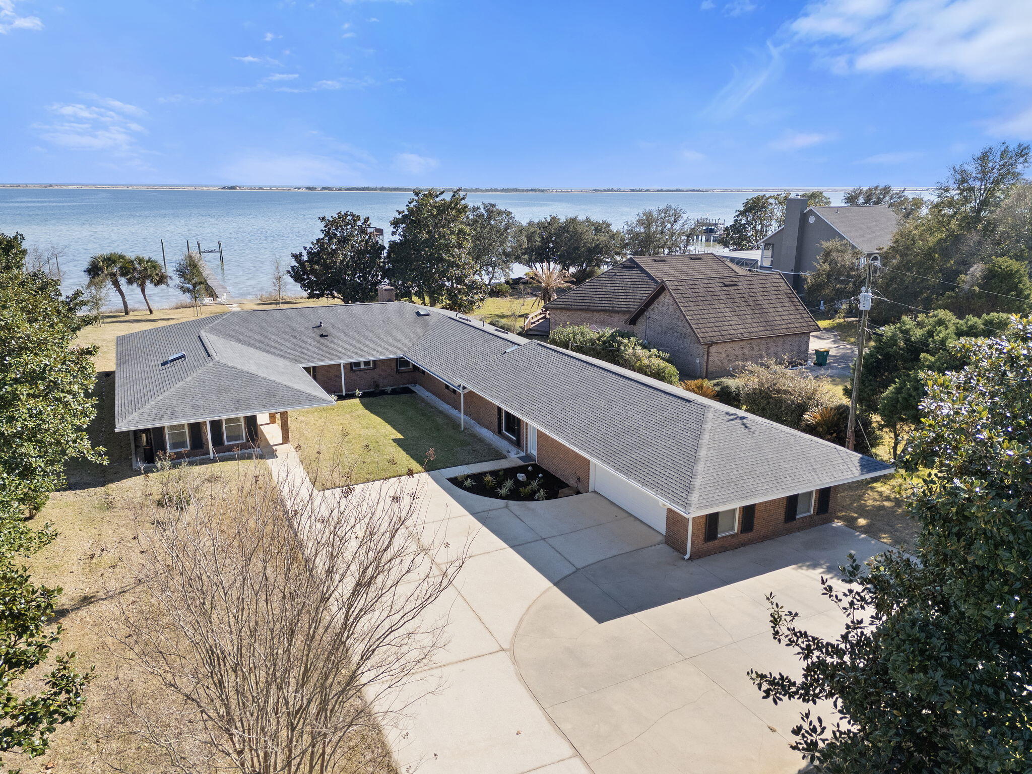 Welcome to this stunning waterfront home, perfectly situated on a spacious 3/4 acre lot with 100 feet of prime water frontage. Designed to take full advantage of its breathtaking surroundings, the home features expansive picture frame windows along the back, offering unobstructed views of the water from nearly every room. Step inside to find travertine floors that flow seamlessly through the living areas, creating a sense of elegance and warmth. The beautiful kitchen is a chef's dream, boasting custom cabinetry, granite countertops, high-end appliances, and a gas range. Open to the living room, it's the perfect space for entertaining while enjoying the serene water views. The large primary suite provides a peaceful retreat, complete with stunning waterviews that will greet you every morning. Additionally, an attached mother-in-law suite offers the ultimate in privacy and comfort, featuring its own fully equipped kitchen, living area, laundry, and bedroom. Outdoor living is equally impressive, with a 2021 dock and boat lift ready for your water adventures. Recent updates include a 2022 HVAC system and a 2022 whole-home generator, ensuring year-round comfort and peace of mind. This exceptional property combines modern amenities with an unbeatable location, making it the perfect waterfront sanctuary for those seeking luxury, convenience, and tranquility.