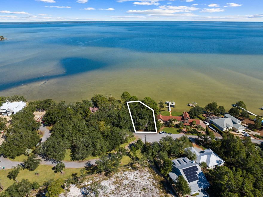 Nestled within the prestigious Pelican Bay Estates, this expansive lot spanning over 100 feet welcomes you to an exquisite waterfront living experience on Choctawhatchee Bay. Unspoiled water vistas stretch to the horizon, framing the perfect backdrop for your vision of coastal serenity.This exceptional property finds its peaceful abode at the end of a quiet cul-de-sac on Shelter Cove Drive, ensuring a serene environment, yet it's just a short 4-minute drive from the vibrant Grand Boulevard. Convenience abounds, with an array of stores and restaurants within easy reach, making daily life both relaxed and effortless.