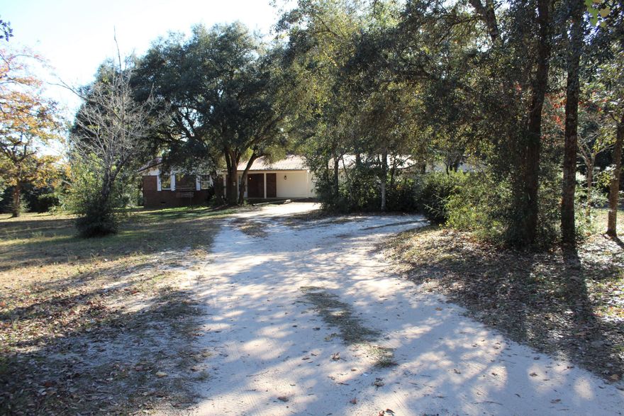 Looking for a few acres to call home?  Check out this brick fixer-upper with about +/- 3.75 acres, close enough to town with all the country charm.  This home sits on two pretty lots (property lines being re-drawn prior to sale) with majestic oaks, some more than a century old! Enjoy the simple pleasures of picking fresh blueberries while listening to the birds sing in your large back yard. There's plenty of space to park under your 1200 sq ft carport and lots of space for your boat trailer, etc. The home has 3 original bedrooms and one and a half bathrooms.  The addition of a 4th bedroom plus sitting area and large walk-in closet (with a separate entrance from the back of the home) offers loads of potential.  This space was plumbed for a home hair salon--water lines in tact/not connected