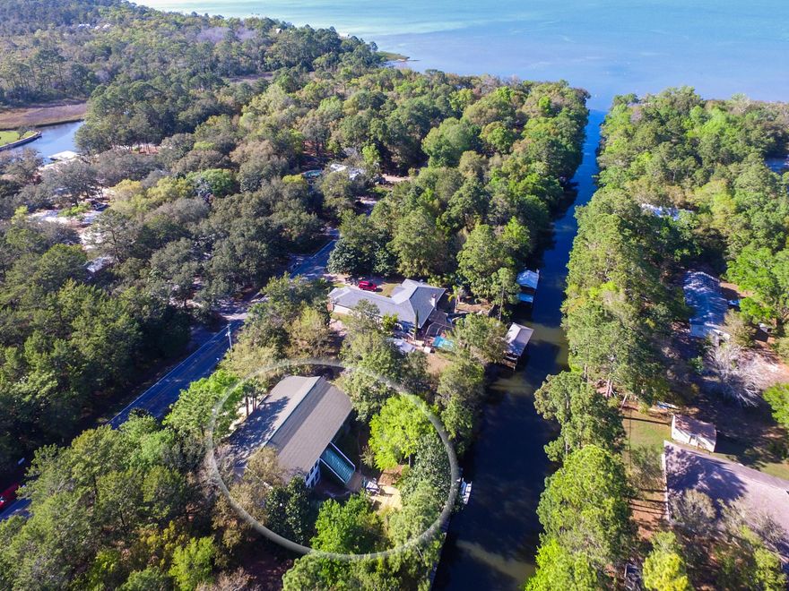 This unique home layout allows great flexibility with its fully livable dual suite floor plan. Expansive stairs lead to a great second story living area with pleasant views of the canal, lush landscaping and treed skyline from the panoramic sun room and over 750 feet of low country porches. This home boasts beautiful views of natural greenery with a great mix of Magnolias, Oaks and Palms. A 75 foot (including floating wave runner dock) runs the full width of the lot providing plenty of space for one or more boats. Deep water access is at your fingertips with just a quick trip down the dredged canal to the Bay. The second level offers vaulted ceilings and two renovated bathrooms. Full Kitchens, spacious living spaces and Washer/Dryers are available on both levels. The utility areas, tool shed, potting table, and 2 car garage provide an abundance of storage with custom shelving. Bonus gift wrapping niche and a wine rack with room for over 300 bottles of wine to enjoy! This home offers great perks! Seller is a licensed real estate broker in the state of Florida.