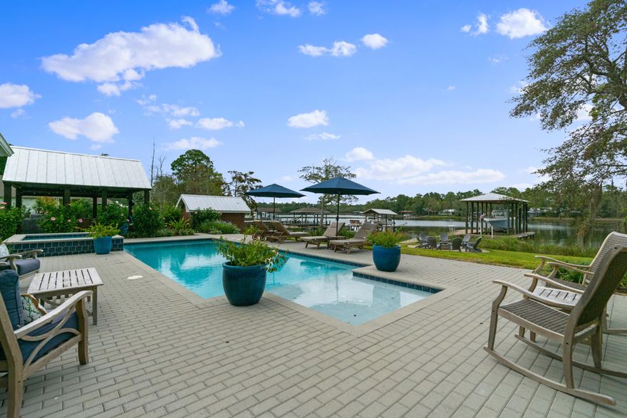 Welcome to Bay Grove Road with the finest in Bayou Waterfront Living, all within minutes to the sugar white sands of the Emerald Gulf Coast! Remodeled and updated, 2,468 sq ft home with 3 Bedrooms, 2 full Baths, multiple living spaces and conditioned garages. The entertaining kitchen serves as the heart of the home displaying Quartz Counter tops, Bosch Appliances, black composite sink, white Shaker cabinetry with soft close drawers. Your backyard heated saltwater pool & spa overlook the calm waters of Mallet Bayou where your covered boat dock with lift will give you and your family various options of how to spend your day. As you enter the front door the 135' of Mallet Bayou lure you through the open floor plan with the dining room surrounded by windows bringing the outside in. Extra large master suite with water views, massive double closets, luxurious soaking tub, and steam shower gives new meaning to master retreat. Tongue and groove whitewashed cedar ceiling crowns the living room with stacked stone fireplace overlooking your backyard oasis with alfresco dining pergola. Gather around the pavered stone firepit with Adirondack chairs for all to experience everything that the Bay Life has to offer.