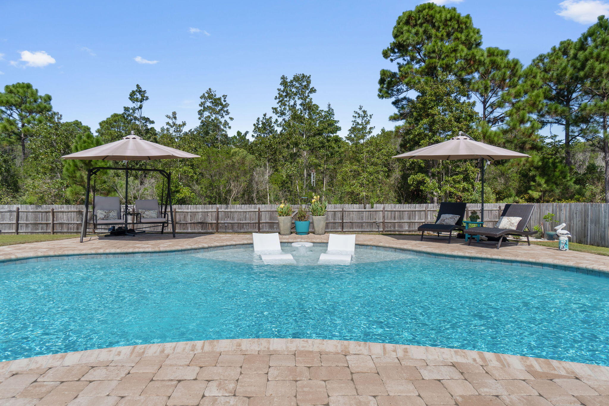 WELCOME HOME to Florida living at its best. This beautiful custom built 3 bed 2 bath POOL home is conveniently located on Whispering Pines Estates in East Navarre. Just minutes to the local stores and the breathtaking white sandy beaches of the Gulf of Mexico.You're 2580q ft. home sits on a half-acre lot that backs up to a conservation parcel to enhance your little piece of paradise with your private gunite pool ~paver pool deck ~ fire pit & undercover porch to cook out and enjoy those wonderful Florida evenings.This custom-built home greets you with a sweeping arch porch entry which opens to the  grand foyer ~home is fully tiled in all wet areas and LVP in the main living areas with high ceilings with crown molding. Open flow into the formal great room overlooked by the Spacious