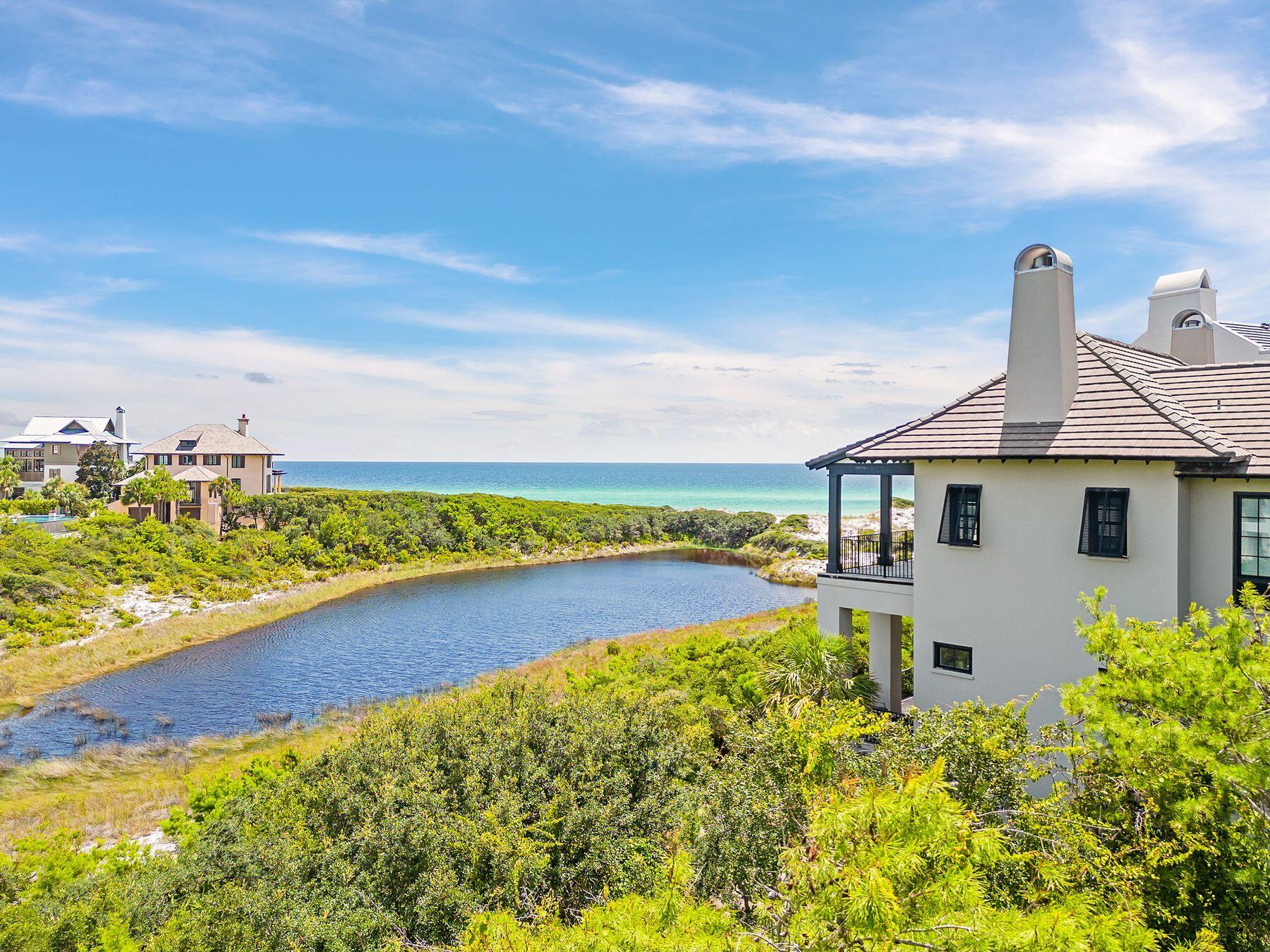 Palatial in scale and design, this six-bed, six-and-a-half-bath concrete constructed home boasts incredible lake and gulf views. Located in The Retreat, this distinguished home is privately situated behind wooden gates and has two large balconies for enjoying the mesmerizing gulf views. All three floors of luxury living can be accessed by an elevator. A sense of arrival is experience as one walks from the grand entryway to the great room, passing a formal dining room with a heavy wood-beamed ceiling. A wet bar is perfectly located for serving drinks when entertaining indoors or outside by the pool. Multiple windows look out onto the serene heated pool and terrace with amazing gulf and dune lake views from every angle. Steps add to the changing dynamics of the grand living space with multiple windows framing lake and gulf vistas. The spacious sitting room is carefully arranged around a chateau-sized fireplace with built-in display shelving on either side. French doors provide a seamless flow onto the generous wraparound terrace with a shady pergola for outdoor living. It's a place to linger and savor gentle gulf breezes and panoramic views. The fully equipped outdoor kitchen is perfect for casual dining and entertaining. An open fireplace adds warmth on cooler evenings. The restaurant-worthy chef's kitchen is magnificently appointed with custom cabinets and granite counters. A large island and a butler's pantry with a wine refrigerator provide additional workspace when entertaining. An impressive Wolf gas stove sits beneath a huge hood in an exquisitely tiled recess. All six bedrooms have their own private baths, featuring custom showers and cabinetry. In the first-floor guest suite, white oak floors resonate with white decor to create a serene ambiance. A sleek private bathroom and an oversized walk-in closet with built-ins complete this beautiful space. The signature staircase is furnished with decorative wrought iron banisters, adding to the timeless styling. A large landing provides an additional sitting area with a TV and wet bar. It's the perfect hub for guests to fix their own breakfast or morning coffee. Lit by a glittering chandelier, the primary bedroom outshines the rest with a fireplace, sitting area and a dressing room with built-ins. It has direct access to a private balcony overlooking the Draper Lake and the Gulf. The spa-like bathroom includes a deep soaking tub, a walk-in shower with a seat and a spacious twin vanity. The third floor is a self-contained den with built-in bunk beds, a wet bar and a sitting area. This exclusive home is completed with a sweeping driveway for parking, a two-car garage and camera security. Located in Blue Mountain Beach, The Retreat is a gated, non-rental community covering 90 acres with just 87 home sites. This exclusive oasis includes areas of conservation and a private white sandy beach on the Gulf of Mexico, with unparalleled amenities, including a newly revamped and private beach club, 1,000 feet of private beach and ongoing dune restoration efforts.