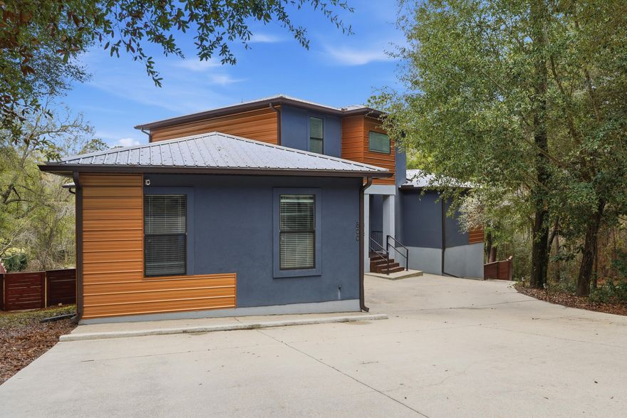 This modern mid-century masterpiece stands as a true architectural showpiece, blending striking character with effortless functionality in a highly sought-after neighborhood. Situated on a quiet street bordered by a serene creek and mature trees, the property offers a rare natural buffer of privacy complemented by peaceful lake views from the covered balcony. The main level invites you into an expansive great room that flows seamlessly to a private deck, anchored by a chef's kitchen featuring sleek concrete countertops, white shaker cabinets, and premium stainless appliances with a gas range. Retreat to the main-floor primary suite, a true sanctuary boasting a massive walk-in closet and a spa-like ensuite with a dual vanity and an oversized tiled rainfall shower. Upstairs, three generous guest bedrooms enjoy easy access to two beautifully updated bathrooms. Designed for both sophisticated living and high-end hosting, the recently remodeled walk-out lower level features durable tile floors, a dedicated home gym, a flexible fifth bedroom, and a stylish bar (which can convey). Outside, the backyard serves as a tucked-away sanctuary with a built-in firepit nestled under towering trees and a modern privacy fence. The excellence of this home extends to its "solid bones," featuring energy-efficient cement-block construction, a north/south orientation to minimize heat gain, a tankless water heater, and a durable metal roof. With over 4,400 sq. ft. of refined living space, exceptional storage--including a large locking gear room--and an unbeatable price per square foot, this home delivers a lifestyle of unparalleled comfort. Experience the pinnacle of contemporary design today; a home of this caliber is a rare find. Tour today!