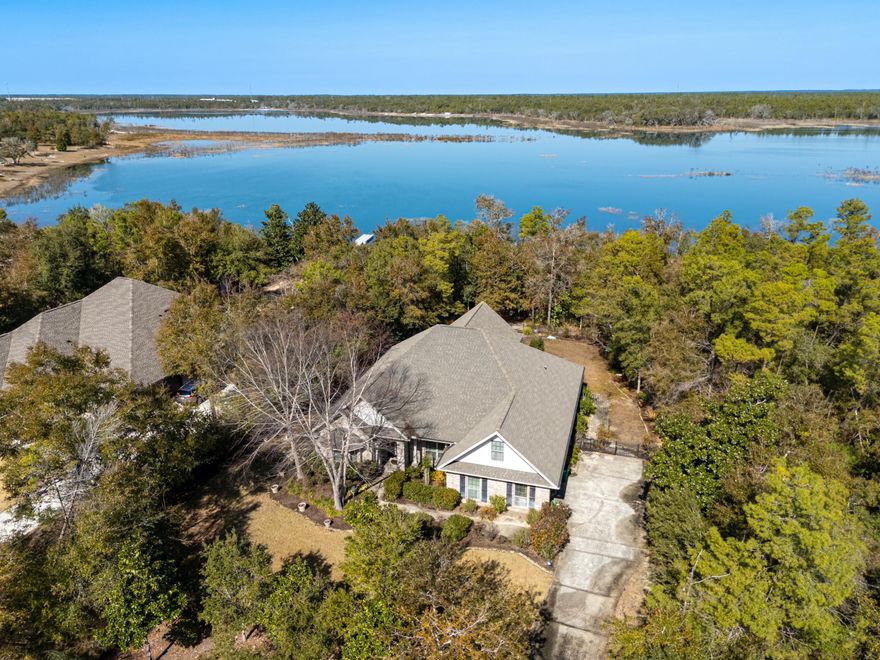 Welcome home to this exceptional lakefront residence prominently situated on Lake Merial. This stunning brick home has been meticulously maintained and upgraded with all the finest features. From the soaring double tray ceilings to the high-quality flooring, nothing was overlooked from top to bottom. Upon entering, the study to the left has built-in cabinetry, a large bay window, and added French doors for privacy. The spacious, open-concept living area provides plenty of room for oversized furniture and hosting gatherings. There is both a formal dining room plus a breakfast table space, not to mention the kitchen with custom cabinets, stainless appliances, granite countertops, and a pantry for additional storage. The HVAC was recently replaced for peace of mind. Adjacent to the living room, the previous patio was enclosed to make a cozy sitting room. This adds to the existing home size to make it a grand 2756 sqft. The generously sized primary bedroom features windows overlooking the lake, both a tiled shower and a tub, a double vanity, and a large walk-in closet with built-in shelving. On the other side of the home sits the second bedroom which also features lakeview windows, a second bath with custom tile shower, plus a third bedroom currently being used as an office. As if that weren't enough, there is an upstairs flex room above the 2-car garage that could be utilized as an additional bedroom, hobby room, or storage space. Finally, added to the rear of the home is the incredible Florida room with a tongue and groove vaulted ceiling, floor-to-ceiling windows for the lake view, and a grill hood for ventilation while grilling. This single-owner home is truly a masterpiece and a must-see. Situated on a hilltop on a unique, approximately 1-acre lot, there is plenty of exterior space to install a pool. The property is adorned with mature trees that provide additional privacy and a more secluded feel. There is an open paver patio and backyard with wrought iron fencing. As an added touch, the seller requested that the pavers be continued down a winding path to the lakefront where there is a two-tiered flat area of pavers by the lake - perfect for comfortable outdoor chairs, a beverage, and tranquility. There is additional wrought iron fencing before the lake's edge. Lake Merial is a gated community that is highly esteemed and enjoys nature-based amenities. Residents enjoy enhanced privacy, scenic walking trails, a picnic area, and access to the pristine 300-acre spring-fed lake. Enjoy fishing, paddle boarding, kayaking, and other water activities right in your backyard. Located only 20 minutes to Northwest Florida International Airport, 20 minutes to Lynn Haven shopping and dining options, and 30 minutes to the emerald waters of Panama City Beach, the location is especially convenient. This home is priced to sell and ready for its next owner. Schedule your showing soon.