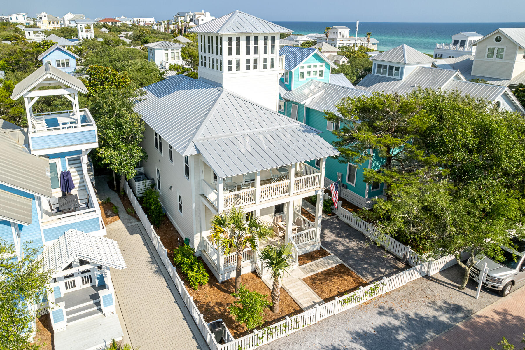 Completed in 2021, the main house is perfectly located just four lots in from 30A. The front porch spans the width of the home and expands the living area to converse with neighbors passing by or play your favorite card game. Once inside, an open floor plan is revealed with ten-foot ceilings and crisp white painted wood walls. The custom built upholstered banquette with storage beneath runs the full length of the dining area. The stylish wood dining table with wicker chairs complements the dining area.  The kitchen is the family chef's dream, starting with a 10' quartzite countertop island that seats four comfortably. Custom-made cabinets offer plenty of storage. Commercial line Subzero refrigerator, Wolf 4 burner gas stove with griddle, white farm style sink, LG dishwasher, coffee bar/ appliance cabinet and white subway tile back splash complete the kitchen. A sand room with sink and storage is located by the side entrance of the home, and just beyond is a half bath. The spacious living area includes 2 over-stuffed white slip covered sofas and chairs. A guest bedroom is currently open to the living area, the addition of sliding doors would create privacy for the 4th bedroom. A full bath is also on the first level.  10' ceilings continue on the second level.  Den with twin sofas for extra sleeping separate the master suite from the guest suites. The black iron king bed with luxurious bed linens creates a cozy retreat.  Off the master is a private porch. The master bath features double sinks, beautiful tile shower, and walk-in closet. Two guest bedrooms, each with private baths and walk-in closets are also on this level.  From the den, halfway up to the tower is a half bath and refrigerator. Continue ascending the stairs to the enclosed tower that extends above the surrounding rooftops, the perfect office, if needed. Step out on to a balcony with panoramic views of the emerald green waters of Gulf of Mexico and extraordinary sunsets. The main house includes a whole house sprinkler system. Rounding out this masterpiece is the separate one bedroom, one bath guest quarters. Built prior to the main house and has been updated. Features include a comfy living area, kitchen, balcony, and washer/dryer. Paved driveway with onsite parking. Excellent location to Seaside town center and amenities.  