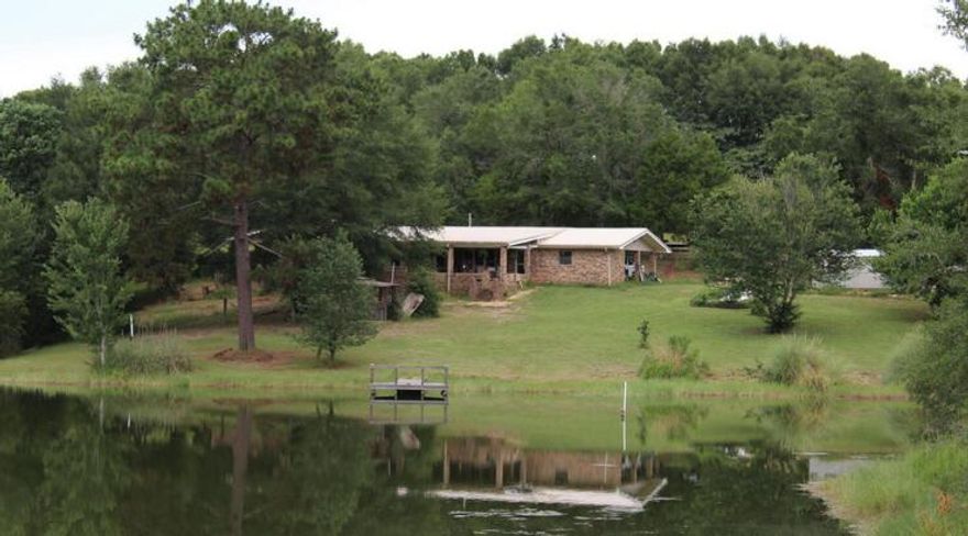 This 24+ acre property has two homes. The main house offers 2100 sqft, large bedrooms, large kitchen, formal dining and a large living room with fireplace. The second home 1200sqft is rented; lease exp 8/2025. This hidden treasure with rich soil and acres of mature blueberry bushes and other fruit and nut trees.  Also features two horse stables and a hay barn. Includes fenced pastures and round pen. The jewel that makes this property one-of-a-kind is the approx. 3-acre spring-fed, stocked pond. This secluded property is great for a farm/ranch or a place to raise a family. Bring your horses, canoes and hunting and fishing gear along with your spirit of self-sufficiency to this country Gem. Buyer/agent to verify all Information.