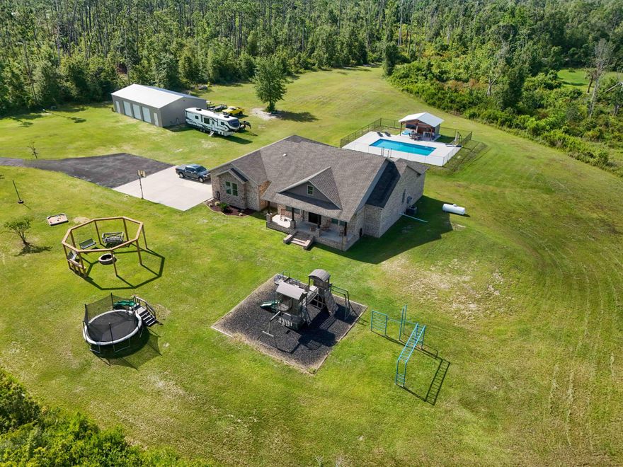 Welcome to this beautiful custom craftsman style home built in 2018 sitting on 7 1/2 acres which offers approximately 3042 square feet of living space. This property sits about 200-300 ft off the main road for all the privacy you would want. This beautiful property features 4 bedrooms with a 5th bedroom converted into an office, 3 1/2 bathrooms and an inviting 18x36ft saltwater swimming pool with an enclosed chain link fence. Outside, a 16x20ft covered pavilion with outdoor kitchen access. Private outside shower with hot and cold water. A 36x60ft enclosed pole barn comes with 3 10x10ft roll up doors, 2 8ft doors, underground power, 50 amp RV hookup, 220 amp outlets located inside of shop and 400 amp service on exterior of the main house. Two car garage with a 40x40ft concrete pad and an asphalt driveway. 

Inside, you'll find an open floor plan with 12ft ceilings in the living room, kitchen, dining and foyer. The rest of the house has 10ft ceilings throughout. Custom trim through the entire house. Master suite offers a double vanity with a 7x4ft walk in shower and soaking tub. This house comes with custom cabinets with Corian countertops and a walk-in pantry. This property is approximately 12 miles from Northwest Florida Beaches International Airport, 17 miles from Pier Park and 6 miles to Lynn Haven. 
