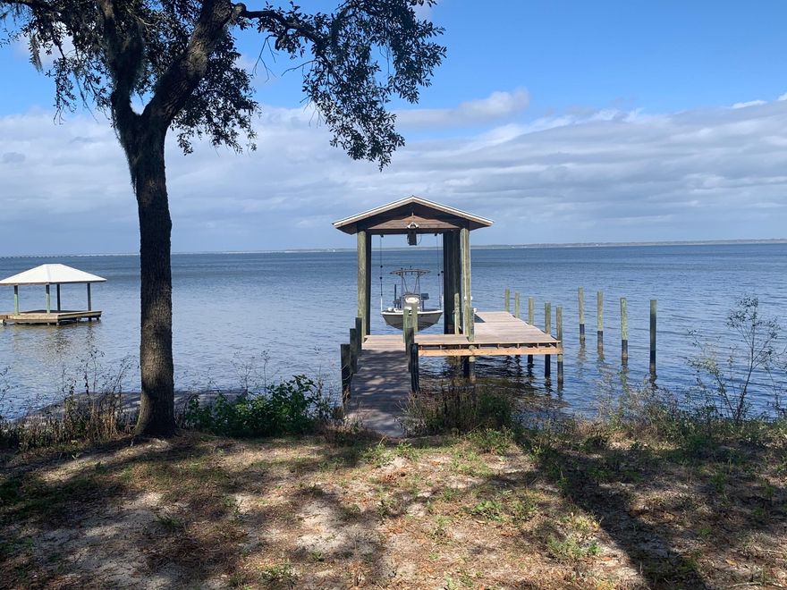 Perfect Bay Front getaway!  100 feet of pristine waterfront with tons of Spanish Moss draped Oak Trees. Incredible views across the Bay to the  331 Bay Bridge and watching boats going up and down the intracoastal water way in your backyard.   Two separate lots of record so subdividing is easy to do. Bayfront living doesn't get any better than this. Large dock with boat lift, seawall with plenty of rip rap. Catch Redfish and Speckled Trout right in your backyard!  Owners use the home as a personal office everyday but will accommodate showings anytime. Kitchen is completely updated. Buyers to verify that which they deem important. All measurements are estimates. Sold AS IS. Listing agent is part owner.
