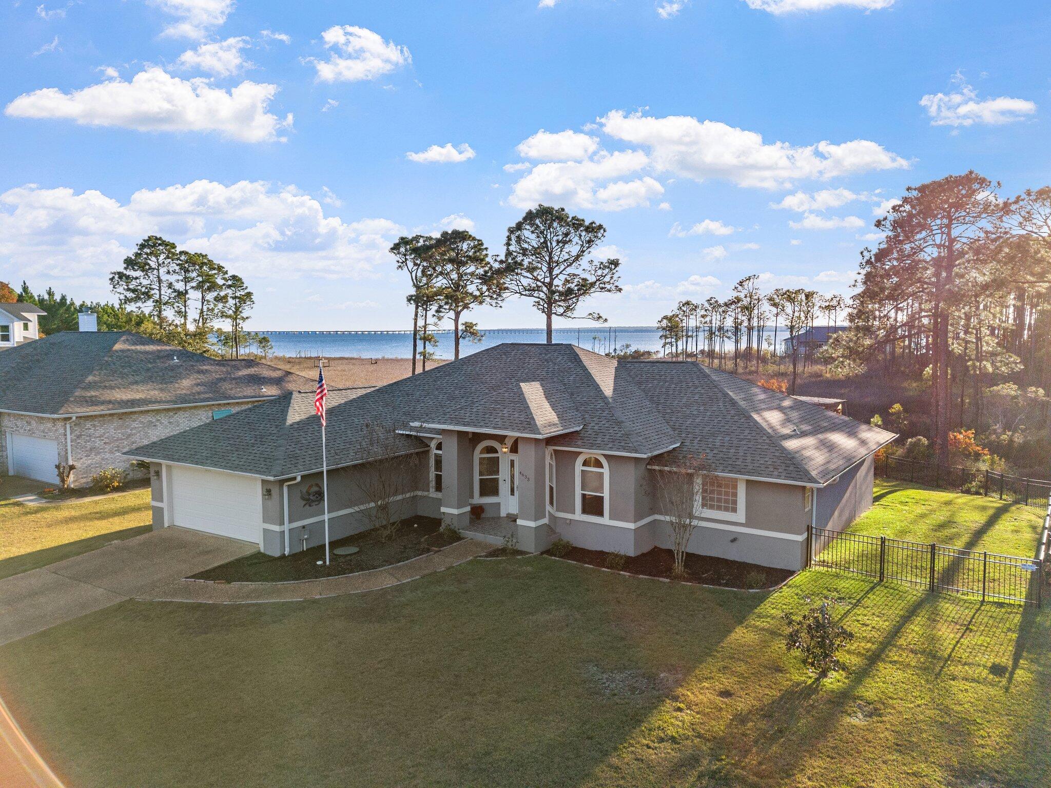 Welcome to the Bayside South Subdivision, where the beauty of nature meets the charm of waterfront living! This stunning home, showcasing breathtaking views of Escambia Bay, is situated on a half-acre lot just minutes from I-10. Discover a kitchen equipped with exquisite custom inset cabinets, stainless steel appliances, and a practical open floor plan, perfect for hosting family gatherings. The extra-large windows invite you to experience spectacular sunrises and sunsets, whether from the spacious sunroom or the custom 1,000 sq. ft. deck featuring a pergola that overlooks Escambia Bay. The backyard is a horticulturist's paradise, filled with a variety of plant species to admire. With soaring ceilings throughout, this residence is anything but ordinary. Enjoy the thoughtfully designed split floor plan, complete with a separate master en suite, garden tub, walk-in closets, and much more. The expansive living room provides ample space for family enjoyment and entertaining. Freshly painted, adorned with beautiful wood floors, and fitted with brand-new windows, this home offers a delightful living experience. Roof is only 3 years old-2021, Fridge, washer, dryer, dishwasher are 2024 models. stove is 2018.