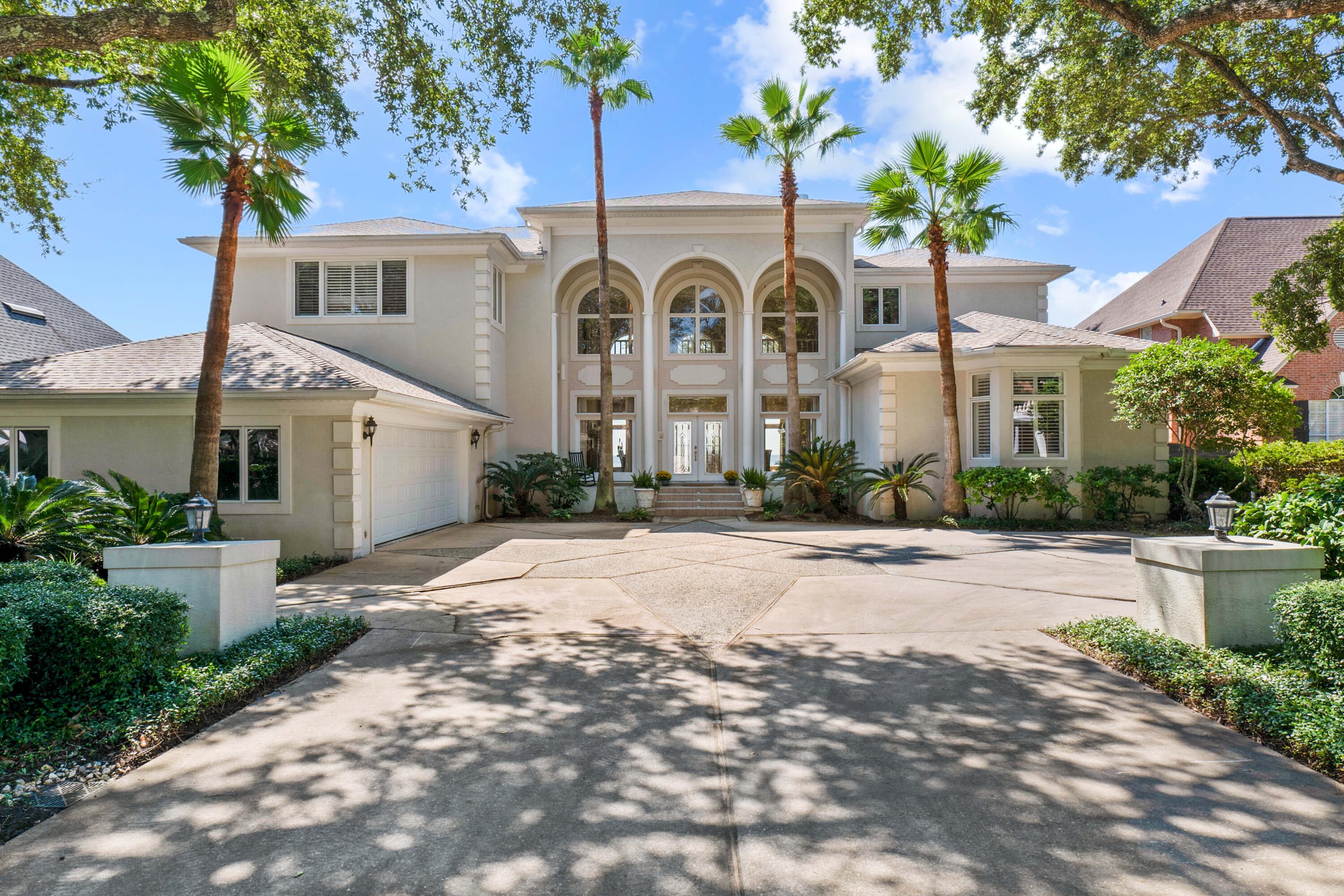 Experience the pinnacle of bayfront living in the prestigious gated community in Bluewater Bay. This exceptional estate boasts 6,230 sq. ft. of luxurious living space, featuring 5 bedrooms and 4.5 bathrooms, and is renowned for offering some of the most stunning sunsets over Choctawhatchee Bay. Set amidst mature live oaks, palm trees, and native Florida vegetation, this home combines privacy with the beauty of its natural surroundings.  As you enter, you are welcomed by a grand foyer with soaring 22-foot ceilings that open into the expansive Great Room, where floor-to-ceiling windows provide breathtaking views of the bay. Elegant custom details such as white oak flooring, mosaic tile work, crown molding, antique chandeliers, and two gas fireplaces enhance the sophistication of the design. The well-appointed kitchen features generous cabinetry, an expansive bar that comfortably seats six, a cozy breakfast nook, and a walk-in pantry, making it perfect for culinary enthusiasts and entertaining alike. Adjacent to the kitchen, the inviting family room is bathed in natural light from large southwest-facing windows, offering spectacular views of the water. Step outside onto a spacious porch that leads to a lush backyard with an elevated sun deck, providing a serene retreat with maximum privacy. The private dock, complete with a swimming platform, boathouse with lift, and fish-cleaning station, is perfect for enjoying all your favorite water activities.  The expansive first-floor master suite features a cozy sitting area with large windows that offer beautiful views and direct access to the back porch. The ensuite bathroom serves as a spa-like retreat, complete with his-and-her sinks, a large walk-in shower, and abundant natural light. An additional bedroom with an ensuite bath is conveniently located on the first floor. The second floor, accessible by two staircases, boasts three generously sized bedrooms, each with windows designed to capture stunning views. A unique rec room with a built-in bar and private balcony overlooks the bay, creating an ideal space for relaxation or entertainment.  Additional exterior features include a well-sprinkler system, an oversized two-car garage, and a spacious decorative driveway. Residents of Windward enjoy access to community amenities such as a central brick-paved gathering park, a 100-foot sandy beach with a boat dock, and a private swimming area. The Bluewater Bay community also offers lakes, sports fields, five swimming pools, a marina, tennis courts, and award-winning golf courses.  This extraordinary estate represents a perfect blend of luxury, community, and the coveted waterfront lifestyle. Don't miss the chance to make this breathtaking property your own ~ a must-see for discerning buyers!