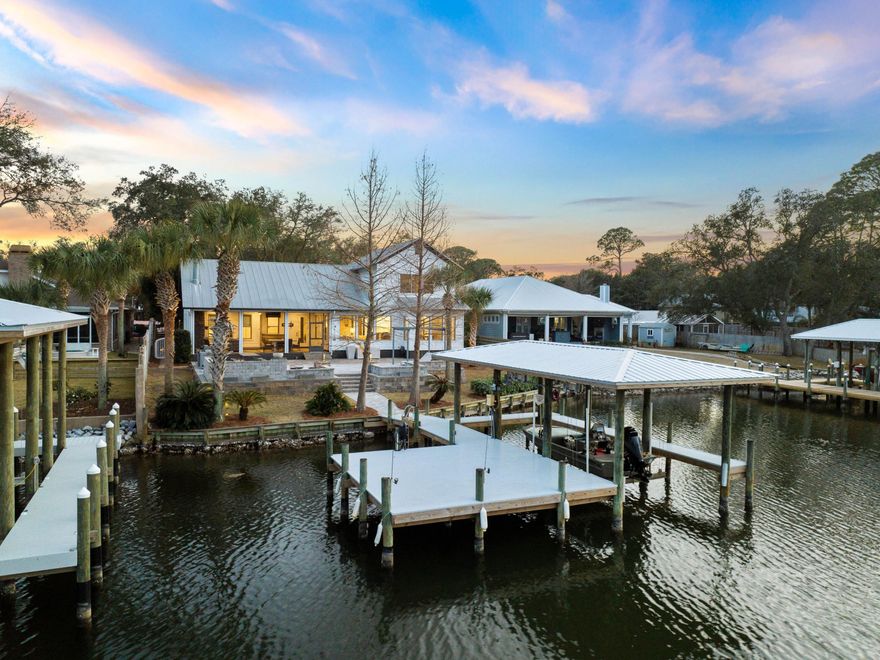 Boasting a stunning waterfront location on peaceful Buck Bayou, this beautiful home sits on a generous lot and is destined for boat lovers. The deep-water boat dock includes a new boat lift and ample space to accommodate all your pleasure craft on the 91-foot waterfront with direct access to Choctawhatchee Bay and the Gulf of Mexico. Recently updated, this immaculate home has a huge open floor plan that includes an e-touch wall fireplace, wainscoting and shiplap accents beneath the coffered ceiling. It creates a clean contemporary living space that's worthy of the outstanding location. The adjoining dining room is equally avant-garde with white oak hardwood flooring and tasteful decor providing a neutral backdrop for the stunning views. A screened patio with gas fireplace and electric shades provides a serene space for socializing and relaxing. The wood-and-white theme continues in the gourmet Milano kitchen with its quartz countertops and pecky cypress accents. Stainless appliances include an oversized stove with hood and a KitchenAid warming drawer and refrigerator gracing the built-in wet bar in the butler's pantry. This amazing home has four beds including two on the second floor. The remodeled master suite has a walk-in closet and stunning bayou views while the adjoining bathroom has a sleek oval tub, his-and-hers vanities and a wet room-style shower with floor-to-ceiling marble-effect walls. The outdoor living space will not disappoint with newly laid pavers on the expansive waterfront terrace. Hook-ups are ready for you to add your own hot tub to this outdoor paradise. Relax on lounge chairs savoring views of passing boats or light up the grill and invite friends round for an impromptu barbecue. Solar lighting and outdoor speakers allow you to create your own perfect paradise. The fenced yard has lush landscaping with automated irrigation and the home has zero HOA fees. The generous lot includes a two-car garage with workshop, storage and a cute one-bed guest house with its own living room and kitchen. The gated driveway provides ample space for parking vehicles and watercraft while a home generator and ring security system provide added peace of mind.
