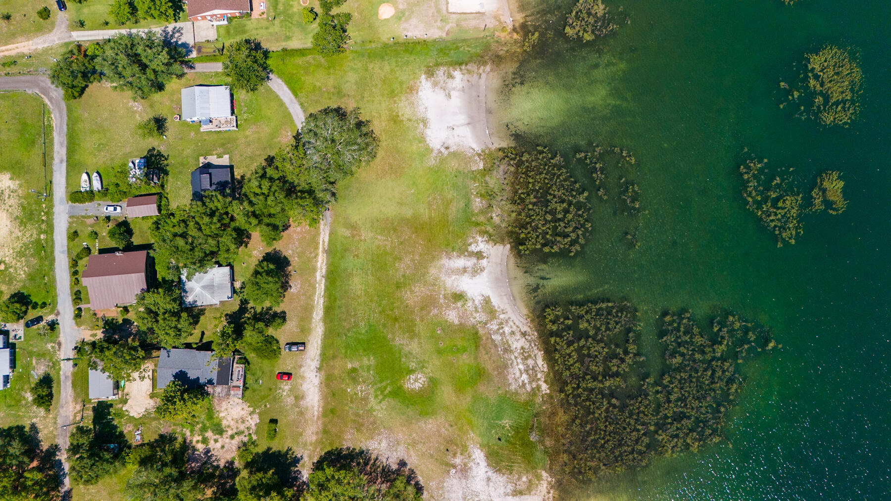 Get ready to make incredible family memories at this log cabin sitting on two lakefront lots with a million dollar view! White Western Lake is one of the most beautiful spring-fed lakes in the area, and while it's only a short drive away from the shops and restaurants of Lynn Haven and Panama City, and is just a 30 minute drive to the world-famous beaches of Panama City Beach, this waterfront location is country living at its finest. Enjoy starry skies overhead, easy lake access for swimming, boating and water skiing, and nearly 600 feet of safe, wide open grassy area between the cabin and the clean, clear water of the lake. The cabin itself was constructed from heart pine logs harvested locally when the house was built in 1960, and are strong and sturdy -- like the old saying goes, ''They don't make them like this anymore!'' The interior of the cabin is a wide open floor plan, with a beautiful wood burning fireplace, with a high vaulted tongue and groove ceiling, with wooden beams and a crystal chandelier adding to the cabin's rustic charm. The smooth poured concrete floor is maintenance-free (perfect for lake life), and two bedrooms, a bonus room, and a walk-in closet line the back wall of the lake house. A wide, screened-in porch stretches the entire width of the front of the house, taking in the breeze from the lake, while the lake views are enjoyed from both the porch and the open floor plan of the living room and kitchen. The double doors that open from the living area to the porch are incredibly solid and fit perfectly, and the original windows throughout the house fit securely while opening and closing easily (again, that classic, quality craftsmanship). Currently it's ready to host summer camp-style get-togethers and overnight trips, or with a little work you could make this your year-round residence. The seller is open to including the bunk beds and queen sized bed, as well as various other furniture and accessories so you can start enjoying lake life and making family memories right away! The White Western Beach Home Owner's Association maintains the road and has an extremely low annual fee (only $47 for the year in 2024). Short term rentals are allowed in this friendly neighborhood of only 11 houses, though currently most homes are either weekend family retreats or full time residences.