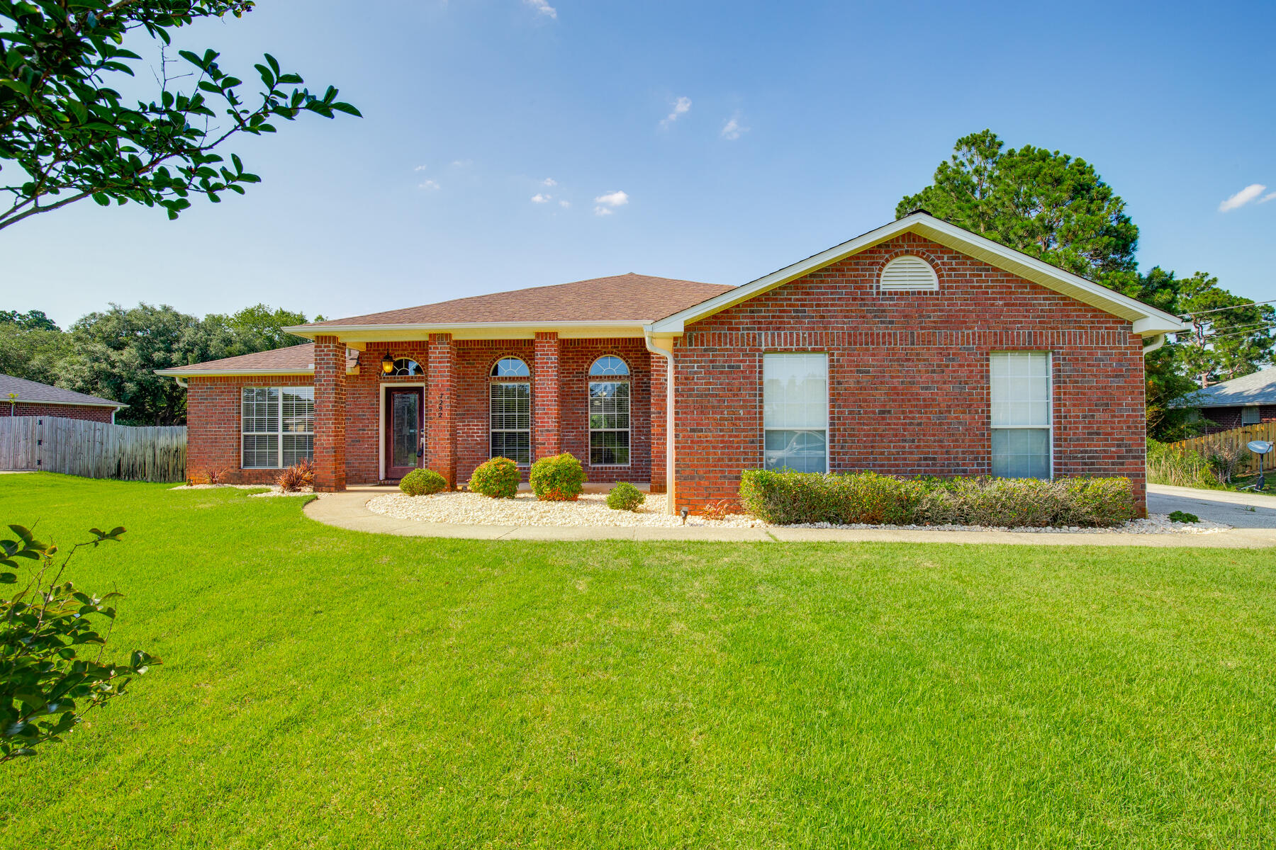 Welcome to this meticulously maintained all brick home in Navarre's Holley By The Sea neighborhood! This spacious property boasts 4 bedrooms, 3 full bathrooms, an office space or bonus room, and a formal dining space. Situated on a 0.453 acre lot with a generous sized fenced in backyard and an extended concrete pad from the side entrance garage and driveway - PERFECT for additional parking or storing your boat or RV behind the gate. Inside this split floor plan home, you'll find gorgeous wood-look waterproof flooring throughout the kitchen, dining, and main living spaces. The eat-in kitchen is a chef's DREAM- with stainless steel appliances, breakfast bar, plenty of cabinet and counter space, pantry, and kitchen island. Looking over the breakfast bar into the living room, you'll see the fireplace and the slider doors that lead to the covered, tiled patio in the beautifully landscaped backyard. Ready for your outdoor entertaining! The primary bedroom has its own wing of the house - just off the living room. Featuring a spa-like ensuite with double vanity, soaking tub, separate walk-in shower, water closet, and a fantastic walk-in closet! On the other side of the house, you'll find the additional bathroom, 3 additional bedrooms - 2 of which share a Jack & Jill bathroom - and the laundry room. Roof replaced in 2014. Brand new HVAC system in 2022, and new water heater in 2021. Outside fence and gates were replaced in 2023. The property also has a garden box, Lawn Pump/Sprinklers, a shed out back for extra storage, and no neighbors behind you. Another perk - enjoy access to all of Holley By The Sea's amenities with your HOA membership - including a boat ramp, 8 clay tennis courts, a community event hall, 3 different pools, exercise room, and more! Schedule your showing today and make this house your HOME!