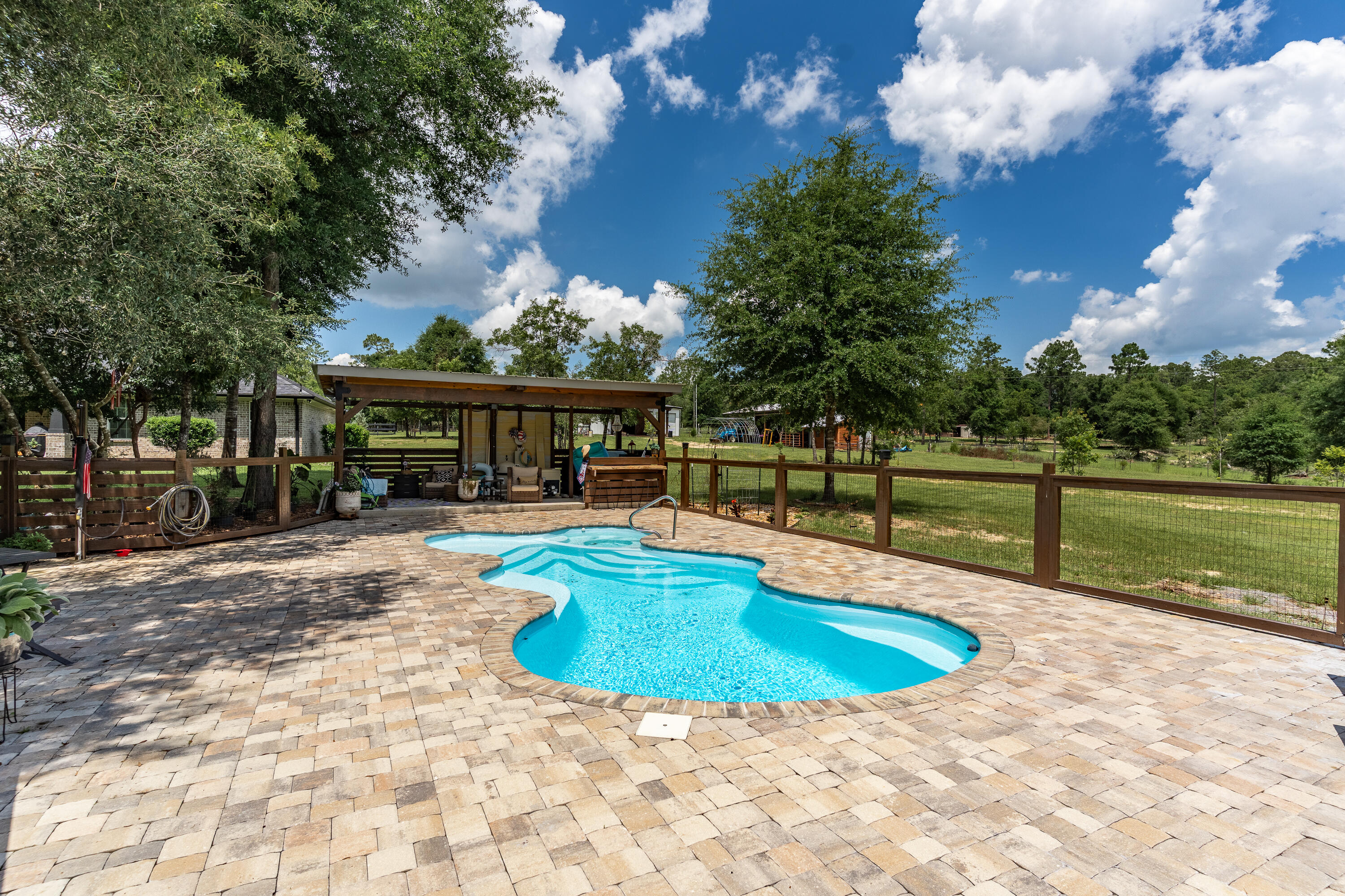 This property is a horse lover's dream, providing everything you need to care for and train your horses. The 24 acres offer plenty of lush pasture for grazing along with ample space for riding. Completely fenced-in property backs up to Yellow River Water Management for privacy. The focal point of the property is the gorgeous brick home. This immaculate home boasts LVP flooring, granite, gas fireplace and an open floor plan. Plenty of room for family and friends to gather while the breakfast bar seats 6 comfortably. The kitchen is designed with ample granite counter space, custom cabinetry and overlooks the family room. A split floor plan provides privacy for the entire family. A Generac whole house generator will provide you with peace of mind. Step outside to discover your personal oasis: an inground salted/heated pool which is perfect for cooling off on warm days and a hot tub for relaxing under the stars after a long ride. An outdoor shower is next to the pool for your convenience. The property has two wells, one measures 350' deep while the other is a spring well measuring 125'. They are tied together. A bubbling stream runs midway down the property. Diverse wildlife frequents the wooded back portion of property.. . This property is perfect for anyone seeking a peaceful, private retreat with plenty of space to roam.