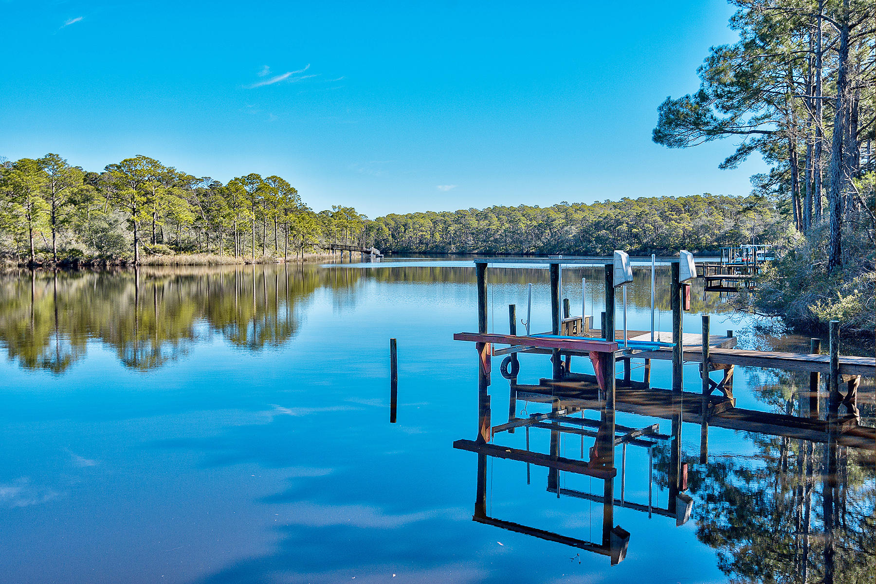 Imagine sitting outside on your private deck, overlooking the largest coastal dune lake in Northwest Florida, with your own dock just steps away. Fishing, kayaking, paddle boarding are all possible ways to spend the day while living in this welcoming home. Between its mature landscaping, outdoor living space, and the tranquil atmosphere of its truly unique setting, whether you prefer an active lifestyle or more relaxed pace, this home is sure to suit a wide range of needs and desires. Once inside this retreat, open living space unfolds, perfect for entertaining or hosting friends and family for the weekend. The well equipped kitchen with large breakfast bar includes a dumbwaiter from one of the two garages to help with heavy lifting.