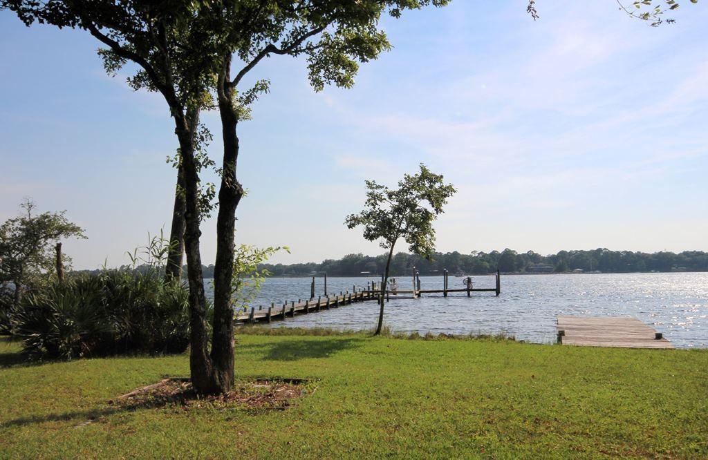 Deep water AND amazing western sunset views of Boggy Bayou can be YOURS! This home sits on gorgeous tree studded .80 acre lot with 100' on the bayou. There is a HUGE multi-level deck along the entire rear of the home which adds to the outdoor living space and is perfect for waterfront entertaining. The large yard offers plenty of space for a future pool and the deep water dock has mooring poles that can accommodate a sail boat. This unique home features a separate suite with its own private entrance for extended family or guests. The guest suite has a bedroom, a full bath, a kitchenette and a living area with large sliding glass doors leading out to the huge back deck. With this flexible floorplan you can have the master bedroom upstairs or downstairsyour choice! Click MORE