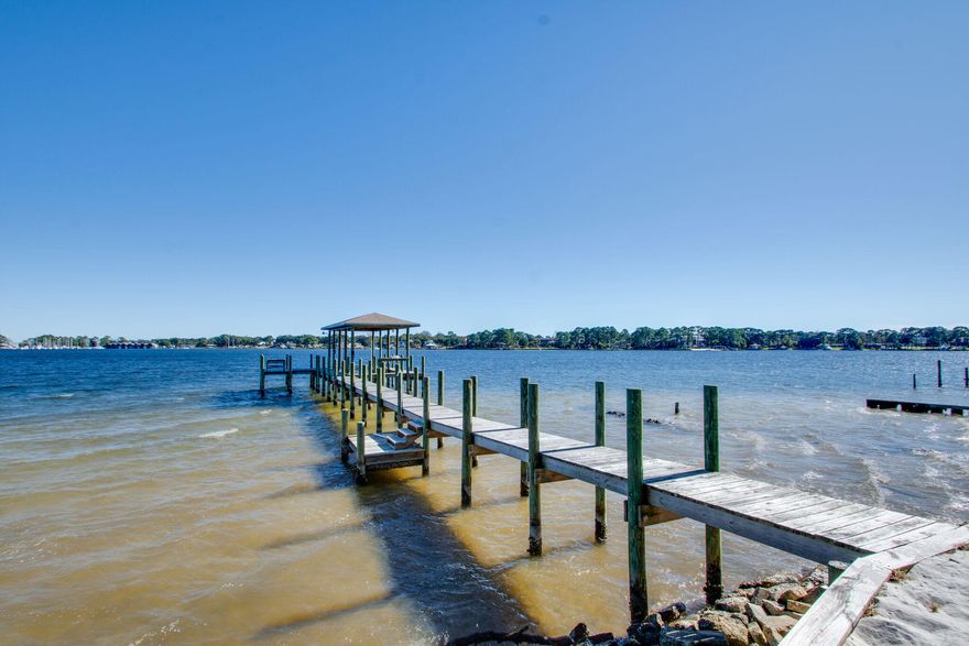Fantastic opportunity to own 125ft of panoramic waterfront in desirable Garnier's Beach. Wake up to the sun rising over this large .58 acre lot facing toward the Destin Bridge and Crab Island. $100,000 in outdoor living updates since last sale. Well-fortified dock, boat lift, and seawall protecting your investment. Beautiful detached farmhouse-style outdoor kitchen and fireplace. White sandy beach areas create a relaxing getaway large enough for beach volleyball.

4 bed 2 bath home with large master and living room featuring stunning water views and large picture windows. Formal dining room, original wood flooring, and recently updated bathrooms.  Kitchen features custom oak cabinetry, stainless steel dishwasher, and double oven.