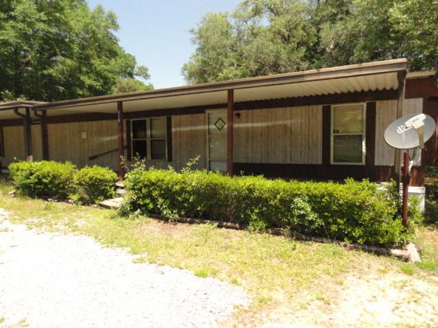 Great investment property or a great piece of property to live in while you build your home. There is a 9x30 covered porch and a 9x35 carport! A circular drive welcomes you to the property. There are mature oaks for shade. The home features a split bedroom design. Natural Gas heat and gas stove. Appliances remain including washer and dryer. Located in the county meaning lower taxes. There is a 2.33 ac parcel next door for sale also.