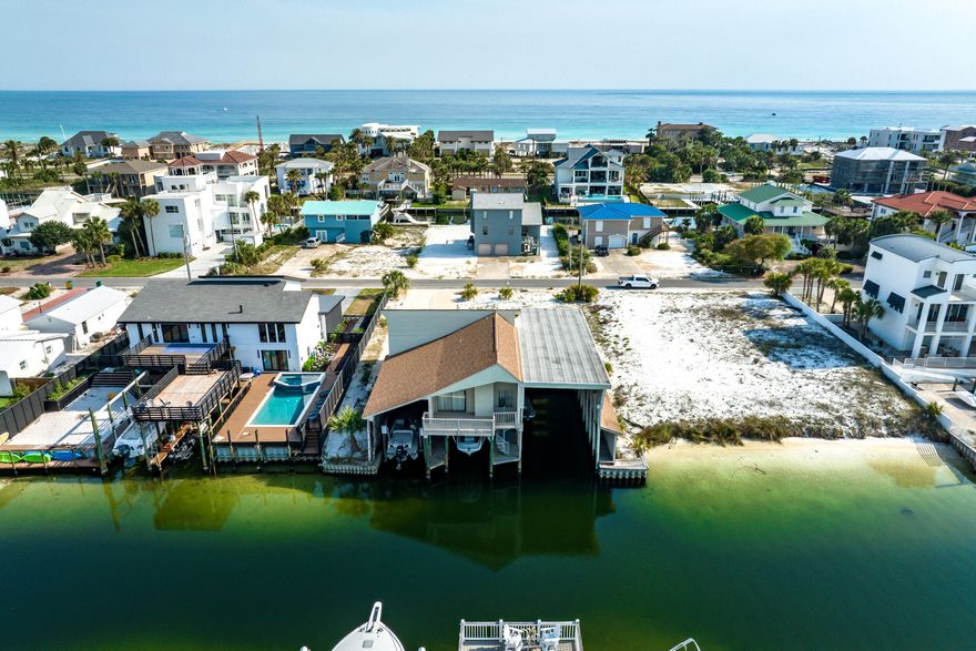 607 Magnolia Drive is a canal-front, two-bedroom, two-bath combination house/multiple covered boat slips, located on Holiday Isle. This is one of the most unique boathouses you'll find in Destin! Below the main house, you will find an unusually large assemblage of three semi-enclosed boat slips, a tackle room, and a garage. The largest slip can accommodate a 60-ft. boat, and the two smaller slips each have their own boat lifts. The main house has an open floor plan. It has a vaulted ceiling in the living/dining room, and a kitchen with a breakfast bar. From the living room, there is alternate access to the boat slips through the balcony and via a spiral stairway. The tackle room contains the washer and dryer and a water closet. The lot provides 90 feet of canal frontage. With a unique network of canals, Holiday Isle (often referred to as Norriego Point) is a sought-after peninsula, located between the Gulf of America and the Destin Harbor - providing easy boating access to the Gulf, the Harbor, East Pass, Crab Island, and Choctawhatchee Bay.