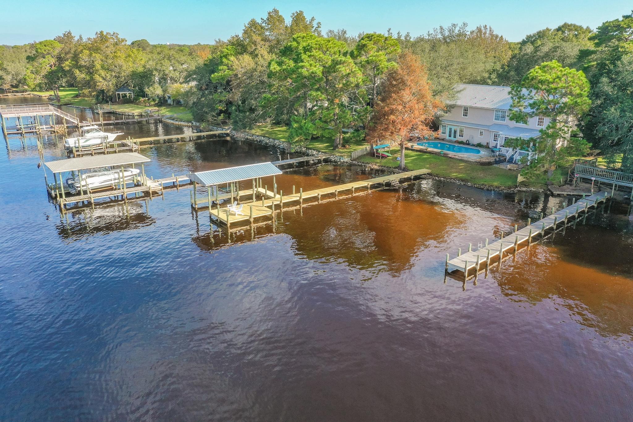 Truly picturesque Waterfront Home with Deep Water Access, Covered Dock, Pool & 5 Bedrooms! This beloved home is tucked away on a private cul de sac in the quaint community of Palm Shores in Shalimar. Rarely does an opportunity come available to acquire a home in this premier community on Garniers Bayou. From the moment you come down the oak lined drive to the home you can't help but recognize the architecture of the home radiating with Southern Coastal Charm. Its expansive wrap around front porch, arched windows, dormer detail, metal roof, carriage style 2 car garage, light colored paver driveway, airy coastal color palette, cheerful shutters & welcoming front door. This home exudes happiness from every angle and has been meticulously maintained by the only owners lucky... (Read More)