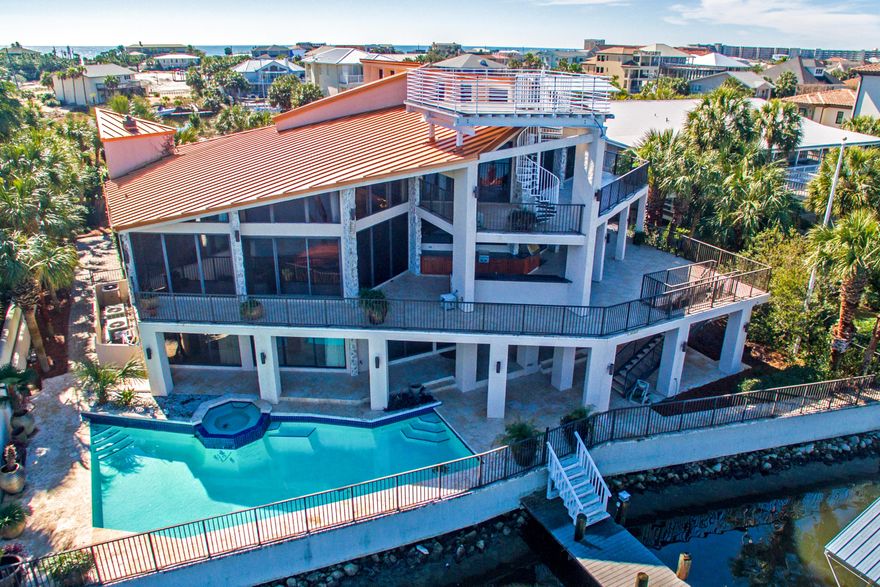 Take a deep breath of sea air, relax, and spread your wings! This amazing home on Destin Harbor is perfect for enjoying an active waterfront lifestyle, fabulously equipped for entertaining, and chock-full of luxuries and conveniences to enhance your daily life. Whether you're hosting a large special event or just getting away from it all, you'll find room to breathe!The property boasts 100 feet on deep water, with 4 boat slips, 2 of which are large enough for yachts, a boat house and lift, and fully equipped dock. The outdoor living space includes extensive terraces, patios, a fully equipped outdoor kitchen, large pool, hot tub, and an incredible rooftop (4th story) tower with a 360-degree view for savoring sunrises, sunsets, fireworks, or starry nights.The home's 7500 SF... ...of heated and cooled space is artistically designed so that the main areas in particular are both incredibly spacious and yet have a sense of intimacy. The current owners extensively renovated and improved the home, adding smart home technology, high-end finishes, and unique design elements so that no rooms are exactly alike. The soaring ceilings and voluminous space of the main floor living area are warmed up by gorgeous 100-year old reclaimed heart pine plank floors and exquisite custom details, including a wet bar with 3 copper sinks, large gas fireplace, climate-controlled wine closet, and of course, the incredible harbor views from the ceiling-to-floor wall of windows. The adjoining circular formal dining area features beautiful lighting and display shelves, while a more relaxed dining area adjoins the kitchen.

The kitchen itself is stunning--both for what it offers and for the luxurious design. The "main" kitchen includes a Dacor double oven, 6 burners, hood, separate warming drawers, hidden dishwasher and fridge, Miele espresso maker, and 3 sinks. In addition, the full butler's kitchen includes another oven, dishwasher, sink, 4 burners, and lots of additional storage. The main floor also includes a powder room, a large bedroom suite, and an additional bedroom or project room with a sink--making it perfect for arts and crafts, for example.

The third floor belongs to the incredible master suite--don't worry, there is an elevator! The huge bedroom, which is well-laid out into relaxing, sleeping, dining, and sitting/harbor viewing areas, includes a mini-kitchen, beautiful built-ins, a gas fireplace, and more floor-to-ceiling views. One-of-a-kind imported doors add a grand statement at the bedroom entrance, as well as at the bath and walk-in closet. Incredible natural textures and materials enhance the spa-like quality of the luxurious master bath: a deep, jetted copper tub flanked by 2 waterfalls, custom copper dual sinks/vanities with concrete-style counters, stone walls, and a rainhead shower with river rock floor. Finally, the bath offers his and hers water closets and walk-in closets (one with W/D). The floor also includes a large loft office area and home gym.

The ground floor features its own living/dining area and kitchen, beautifully decorated with Venetian plaster walls, modern fixtures, and travertine floors; 3 bedroom suites, including another master; a large utility room; additional storage; and a 3-car garage. The home includes 7 A/C units, an incredible amount of storage space, automated blinds, security system, gated entrance, and much more! This amazing residence offers great luxury and convenience for a truly relaxing lifestyle, the opportunity to fully enjoy world-class water sports from the comfort of your own home, and/or a very special rental property with the potential for strong income--all at an excellent value. 


