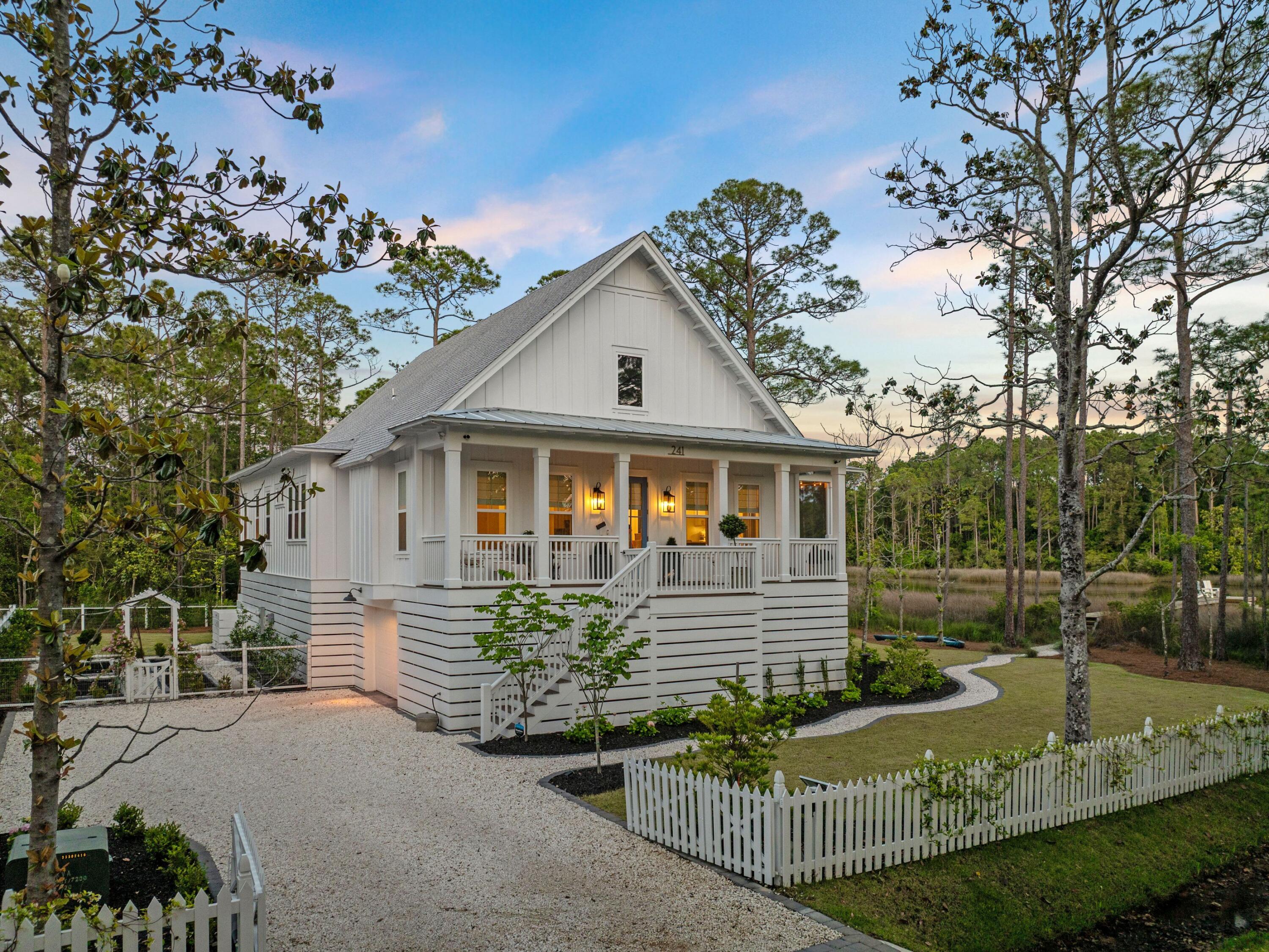 Nestled among the forest pines, this newer construction home is a haven of serenity. Located on a large lot overlooking Hogtown Bayou, this contemporary Florida cottage has a private boardwalk leading through the reeds to a fishing dock. Enjoy sunset drinks and waterfront views or launch kayaks, paddleboards and jet skis right from your own backyard. Steps lead up to the open porch of this elevated home, which is perfect for enjoying sunshine and shade in all seasons. Lofty 10-foot ceilings welcome you inside, where the living room is saturated with natural light through multiple windows. Engineered hardwood flooring flows through a synergy of open spaces, each with its own designated purpose. Anchored by a gas stone fireplace, the sitting area offers a place to kick off your shoes and relax. A generous dining area provides a space for everyday meals and entertaining beneath a contemporary light fitment. Head into the all-important kitchen that's designed for channeling the inner chef. White Shaker-style cabinets stretch to the ceiling while tiers of drawers store utensils and smaller items closer to hand. Veined Cambria Brittanicca quartz countertops extend onto a large island that accommodates a stainless steel butler's sink, dishwasher, microwave and still has space for four diners. Tucked away, there's a handy wet bar with a beverage refrigerator and shelves for holding glasses, mixers, and more. Three beautifully designed bedrooms boast custom closets, elegant Roman blinds and blackout shades. After a peaceful night's sleep, awaken to water views and access to the balcony from the second bedroom. The master suite is particularly enviable with space for a quiet sitting area and another door to the balcony. A wall of windows frames serene views of Hogtown Bayou. The adjoining bathroom has an oval soaking tub, a glass shower enclosure and a twin vanity, all enhanced by a feature tile wall. A separate laundry room, home office space, bunk area and a guest bath round off the first-class amenities.
There's no shortage of outdoor living space with a lengthy screened balcony on three sides providing space for relaxing, dining and socializing beneath gently turning fans. Built on 10-foot pilings, the home includes a garage for storing bikes, garden equipment and water toys beneath the house. A Bahama rock driveway with automatic gates ensures privacy and security for part-time residents. The well-tended garden provides a riot of summer color, grass for children to play, and the opportunity to grow your own fruit and veg, if desired. Close to the Cessna boat launch, owners can look forward to endless watersports and happy days spent at one of the beautiful white sand beaches nearby. Gulf Place and an abundance of restaurants and shops round off a variety of activities that can be enjoyed from this most desirable location.