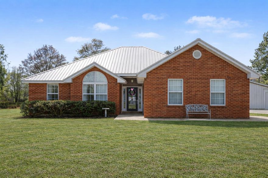 This 1 owner stunner, set on 2 private acres, is a beautifully maintained brick residence blending refined comfort with exceptional functionality. Soaring ceilings and tile flooring throughout the main living areas (Bedrooms 2 & 3 feature LVP) create an elegant, cohesive flow. The spacious kitchen offers abundant cabinetry and NEW updated appliances including a refrigerator, sink and microwave. Additional improvements include a new metal roof (2023) and new water heater (2026). Enjoy peaceful mornings beneath the expansive covered patio with fireplace overlooking the open acreage. The impressive 36x64 workshop with 220 power inside and out. A newly added drive provides seamless access from the main driveway to the workshop, enhancing both convenience and curb appeal.