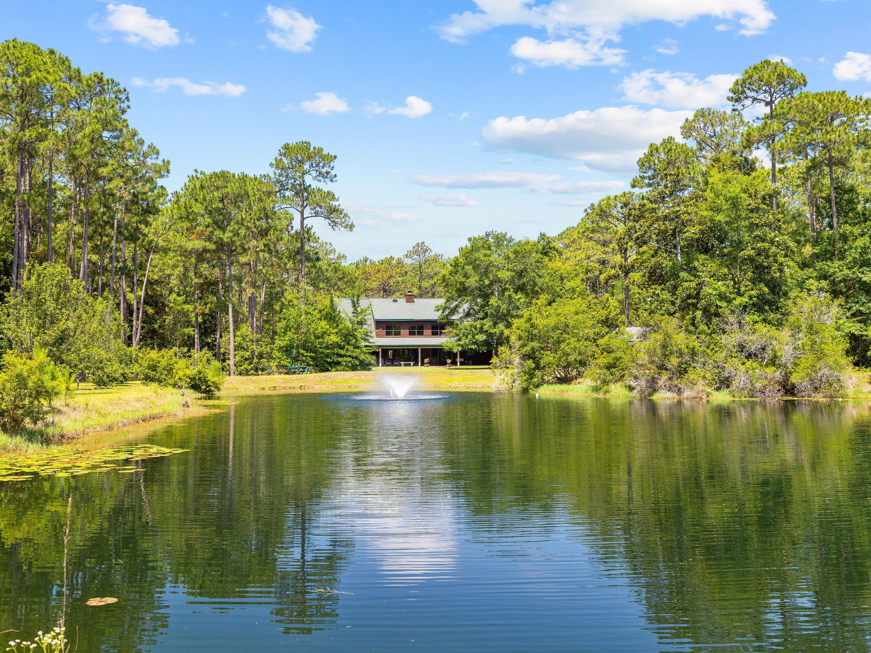 SELLER FINANCING AT 5% FIXED: Imagine owning your own woodland retreat on 20 acres close to bay access and the beach. It's the perfect retreat for those who value privacy and want to be surrounded by nature. Relax on the back porch looking out across your own stocked pond listening to the tinkling fountain and sounds of nature. There's nothing to mar the view of mature pine trees and native greenery. This four-bedroom, three-bath home is in keeping with the surroundings as a two-story luxury log home with timber walls and ceilings. It has a vast open living room with a high vaulted ceiling, LVP flooring and a floor-to-ceiling woodburning fireplace. When you fancy entertaining, this is the perfect space for hosting memorable celebrations. Horses Allowed