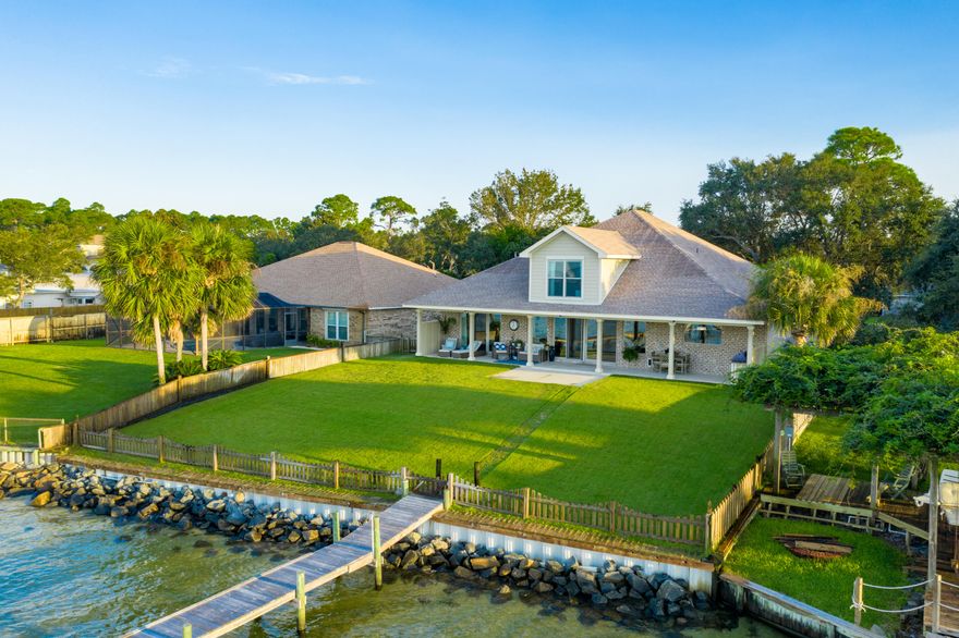 Welcome home to waterfront leaving at its best .....Simply Stunning Custom-Built home nestled on one of the most picturesque locations in East Navarre offering a private 240 ft. dock, 6,000 Lb. boat lift, and seawall overlooking the Santa Rosa Sound and Navarre Beach! Enjoy breathtaking sunrises and sunsets daily on your 52 ft back porch....perfect for spending time outside with a soft coastal breeze and your Summer kitchen to make the most of the wonderful Florida evenings to cook out and entertain. Home is only 5 years young exquisite inside and out. On entering the home you will immediately appreciate the attention to detail and the coastal living theme with high ceilings ~crown molding, wood plank tile flooring all enhanced by the soft color palette of grey and white for a light.... fresh and bright feel in every room.

 A wall of windows across the entire living area brings the outside in with amazing panoramic views of the water and Santa Rosa Island ~Living room features built in bookcases on either side of the Natural gas focal point fireplace, Surround sound with 5 built in speakers ,recessed lighting and floor outlets~ open flow to the dining area with decorative columns and detail knee walls set the stage for a great entertaining area or formal dining.

Gorgeous Gourmet custom designed kitchen is framed by a beautiful brick archway ~ ceiling height solid wood shaker cabinetry with soft close doors and drawers, pull out shelves, lift platform for a blender, center island has a prep sink & drop down seating area with banquette bench & storage~ 48 " Jennair Gas cooktop with griddle and grill .Decorative mantel hood with pull out spice racks ~built in oven and microwave ,elevated dishwasher and large single under-mount porcelain sink ~ Huge walk in pantry with shelving and 16" bottom shelf with electric receptacles for your favorite appliances. Heart of the home in the kitchen is enhanced by the picture swept head window for wonderful water views. 

Master retreat on the first floor enjoys breathtaking water views with sliding doors out to your private back patio with remote control black out blinds- double stepped up ceiling with crown molding & gorgeous wood plank tile flooring ~master bath enjoys separate granite vanities ,sound speakers ,free standing soaking tub and huge step in tiled shower ~master closet has his and her shelving areas ,built in ironing board and shoe display shelving.
Additional bedroom suite on the first floor is private and accessed through double doors ~ two bedrooms with deep closets and a private bathroom with free standing granite vanity and 5 ft step in shower.
Beautiful wood spindled staircase leads to the huge bonus room 31 x 13 that could be used to suit your lifestyle needs as a guest/ teenage suite /playroom or media area with wonderful views over the water and a spacious separate bathroom with vanity and step in 5 ft shower. Bonus room has a huge walk in closet /storage room 15 x 6.

Downstairs laundry has built in shelving ~hanging racks and a large storage closet ~open to the wrap around office and craft area with lots of cabinet space ,granite countertops and sink area .Home offers plenty of parking space and your 3 car garage is 27 ft deep so can house your larger vehicles and you still have a 6 ft work area and room for all the beach toys.

Your backyard oasis awaits with beautiful Zoysia luscious lawn with irrigation well & timer for effortless care in the summer months ,long covered porch has plenty of room to accommodate long lounges ~ gathering garden set and a full outside dining table area to enjoy the evenings when cooking our in your outdoor kitchen with storage, granite countertop ,prep sink and built in Napoleon 48" natural gas S/S grill with infrared seerer and rotisserie .

Private dock is 240ft with a 4ft walkway and the boat slip will accommodate up to a 10ft boat with a 6,000 lb lift, enjoy walking out to watch the boats roll past and the dolphins play. Only minutes on the boat over to Navarre Beach or a short distance down the Santa Rosa Sound to all the ride up restaurants in Pensacola or a gorgeous ride down to Destin and Crab Island, both with pass access out to the Gulf of Mexico. Stroll back to your dock after a day of fishing and clean off the fish on your S/S fishing table ready for dinner.....Pilings are already installed for a future roof over the boat slip.

Home Features: -
*12 ft glass sliders in the living room & 9. ft glass sliders in the master along with the upstairs window are impact glass, all other windows have Fabric Shield hurricane panels.
* Back wall is supported by a 3ft x 3ft x 3ft concrete footer with 6 rebar for any potential erosion that may occur.
* Speakers with remote control on the back porch ~ home is wired for cable or satellite and has full security system with two keypads.
*Whole house central vac with an automobile vac in the garage.
*In wall pest control system which allows your provider to control bugs without coming in the home.
*80 Gallon gas water heater.
*Foam insulation and dual zone central heat and air unit with two thermostats.

are to name a few of the features of this amazing waterfront home ...click on the link to enjoy the video walk through of this home~ call today to make an appointment for your private viewing ~come and see how amazing living can be on the water .....




