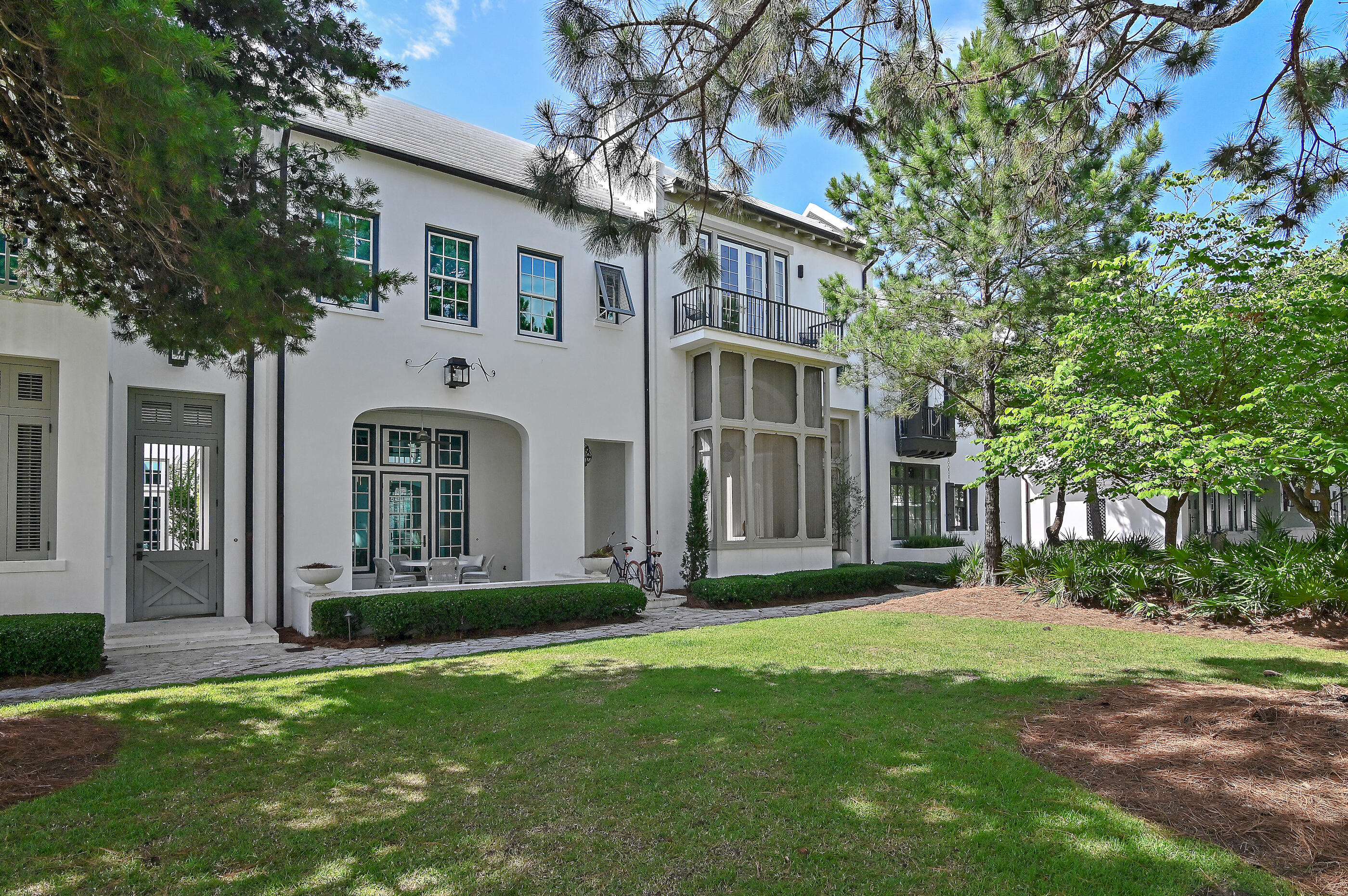This masterfully designed residence by acclaimed architect Gary Justiss is a stunning expression of courtyard living--seamlessly blending classic architectural elements with modern luxury.Perched along the edge of lush Arboleda Park, the home welcomes you with a gracious park-front loggia. Framed by elegant arches and thoughtfully outfitted with a built-in alfresco kitchen and comfortable seating, this open-air space is ideal for both intimate evenings and effortless entertaining. From here, enter the main living area or pass through the private zaguan into the serene heart of the home: a sunlit courtyard with a soothing water feature. Inside, the residence unfolds with soaring ceilings, hand-applied Venetian plaster walls, and exposed wood beams that evoke a quiet sophistication. Every space is crafted with intention from the second-floor flex room offering versatility for work or relaxation, to the coveted primary suite with its peaceful sitting nook.
The sleek white kitchen is a study in refinement, anchored by a wall of French doors that open directly to the paved courtyard, blending indoor comfort with outdoor tranquility.
This exceptional home is more than a residence it's a statement of grace, serenity, and architectural excellence. A rare opportunity to experience the soul of Alys Beach through one of its most thoughtfully curated homes. located just one block from the Zuma Fitness Center and Clermont Courts, and only two blocks from the iconic Caliza Pool, this residence offers easy access to Alys Beach's most desirable amenities yet remains a peaceful retreat in the heart of the community.