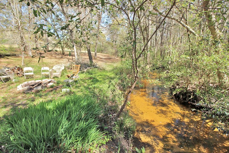 This short sale is a darling creekfront getaway on just under 10 acres only 2 miles north of DeFuniak Springs. The sandy bottom creek is always flowing and has a walking bridge to the other side. Pasture with horse barn and stalls on the front 2 acres - heavily wooded in the back for privacy. Less than 2/10 of a mile from Hwy 83 and yet it feels like it is a completely private oasis away from the world. The cabin is rustic and cozy, with the master bedroom and bath on one side and two other bunk rooms on the other. The back yard is shaded and butts right up to the creek, flowing the entire width of the property. Sit and swap stories and roast marshmallows at the creekside firepit. Don't wait to see this one - 10 acres with a creek near town is hard to come by and likely to go fast!