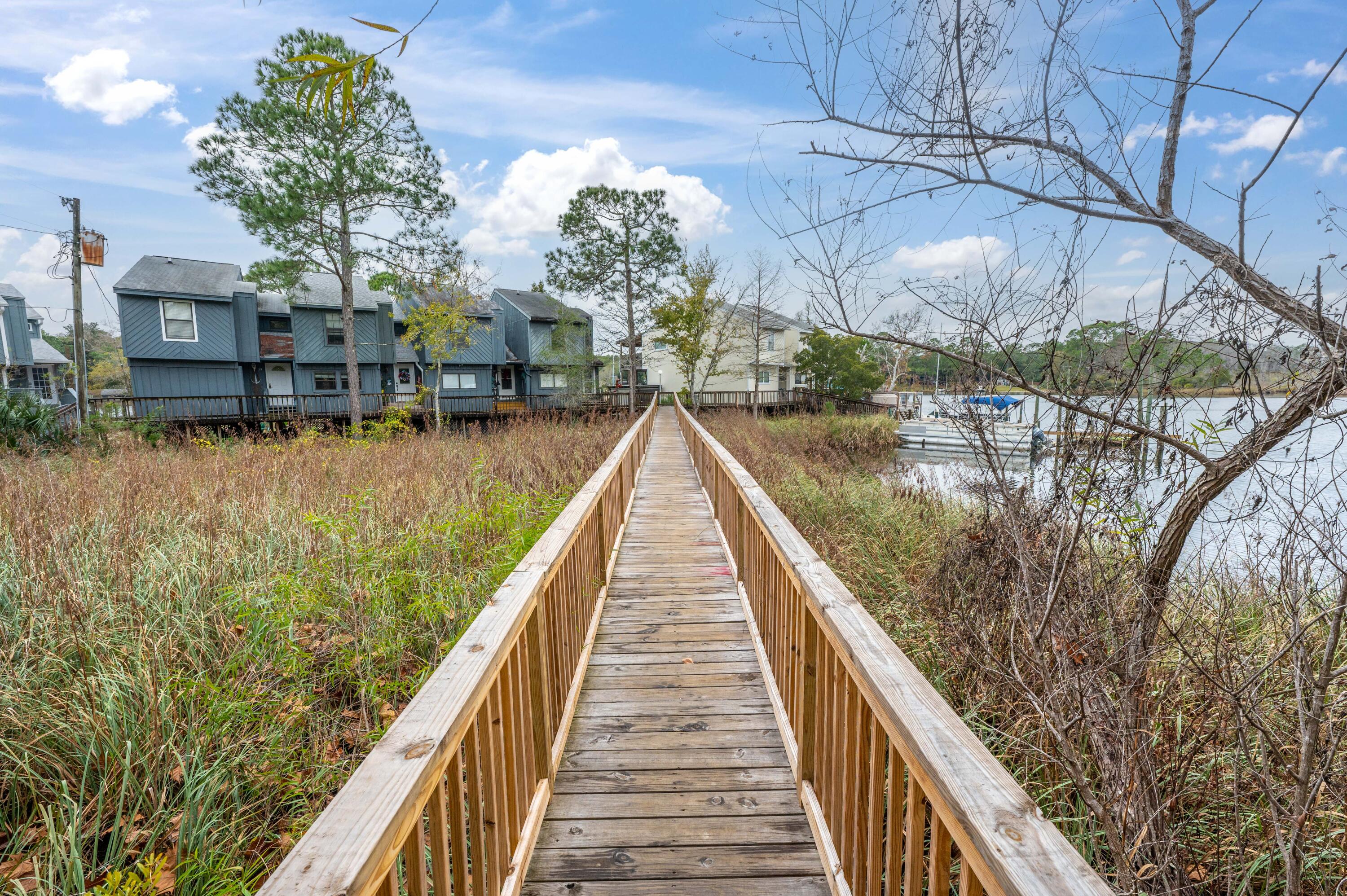 Niceville End Unit Townhome on the Bayou.Entering, note the natural wood of the stairs to the second floor.  The hallway, featuring LVP wood-look floors, leads to the first bedroom on the left with large dual closets.  At the end of the hall is the primary bedroom with a full bath and balcony deck overlooking the bayou, perfect for sweeping views to start the day or a relaxing place to wind down in the evening.  Upstairs, a large living room features sliding door access to a second floor balcony overlooking the bayou. A hallway off of the living room leads to the kitchen, full guest bath and an additional guest room / office. This end unit townhome also comes with two assigned parking spots.  A great investment opportunity, this townhome is sold as is