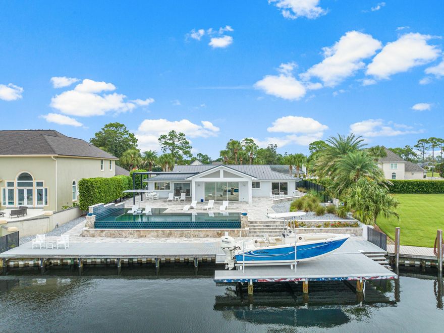 This exceptional Bay Point retreat is a boater's paradise, located on the shores of the scenic Grand Lagoon with convenient canal access to a host of water-based adventures. A sweeping circular driveway provides ample parking along with a two-car attached garage. More impressive still, the backyard greets you with views of an inviting infinity edge pool. The outdoor oasis continues with a hot tub, gas fire pit and covered travertine patio. At the water's edge, you'll discover your own private deep-water dock, offering convenient access less than a mile away from the pass. This exclusive feature includes through-flow decking and a hydraulic boat lift for your enjoyment. Step inside to find this spacious ranch home that has been completely renovated from sleek travertine floors to an aluminum seamless roof. A synergy of open living spaces provides enviable areas designed for laid-back living, relaxing and entertaining. The open living room and dream kitchen deliver breathtaking views of the open bay and pool. Laid out for living all on one level, this beautifully presented home also has three beds and three modern baths. As well as delivering superb boating activities, this prestigious gated community has an enviable championship golf course to challenge and delight. The newly opened Point South Marina offers sheltered slips with easy access to the Gulf of Mexico and Intracoastal Waterway. It's the perfect base for endless days spent fishing, boating and enjoying the open water.