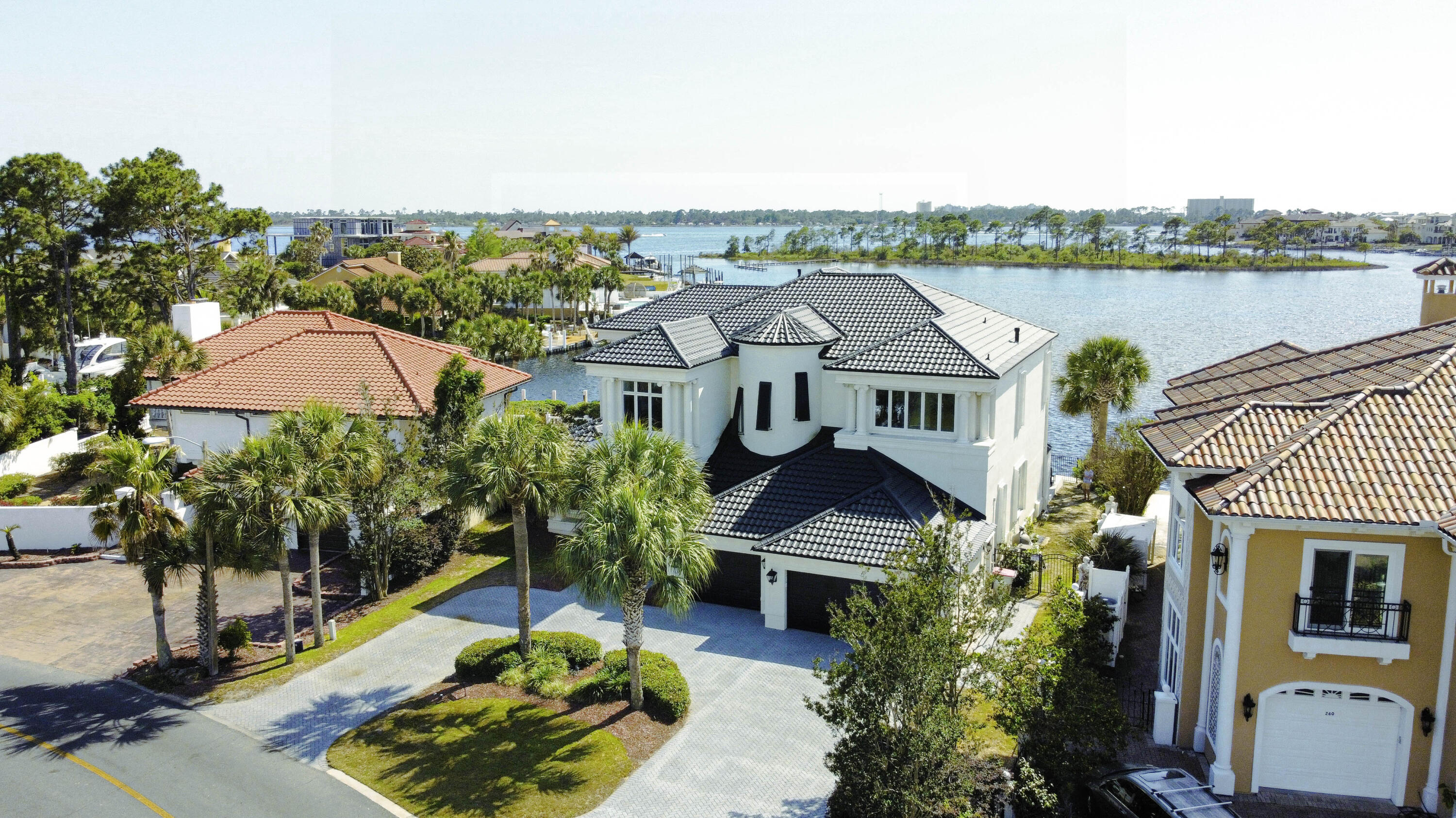 This passage describes a modern American home designed to evoke a sense of wonder, with exquisite finishes and breathtaking views of the Grand Lagoon from all angles. The property has 106 feet of deep-water frontage, a backyard dock, and a heated pool that offers indoor-outdoor living. The owners recently installed a changing room for your convenience when you are lounging around at the pool. The chef's kitchen features a waterfall black-honed granite center island and other high-end features like double ovens and a subzero. The main floors are adorned with marble of various depths and colors, while the master and second levels have contrasting black wood floors. The 3-car garage provides ample parking space and a circle drive with room for more parking as needed.