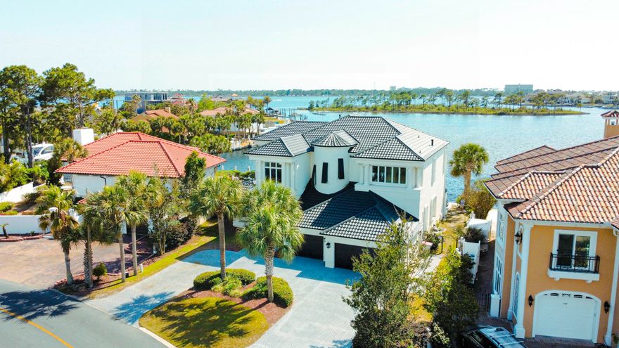 This passage describes a modern American home designed to evoke a sense of wonder, with exquisite finishes and breathtaking views of the Grand Lagoon from all angles. The property has 106 feet of deep-water frontage, a backyard dock, and a heated pool that offers indoor-outdoor living. The owners recently installed a changing room for your convenience when you are lounging around at the pool. The chef's kitchen features a waterfall black-honed granite center island and other high-end features like double ovens and a subzero. The main floors are adorned with marble of various depths and colors, while the master and second levels have contrasting black wood floors. The 3-car garage provides ample parking space and a circle drive with room for more parking as needed.