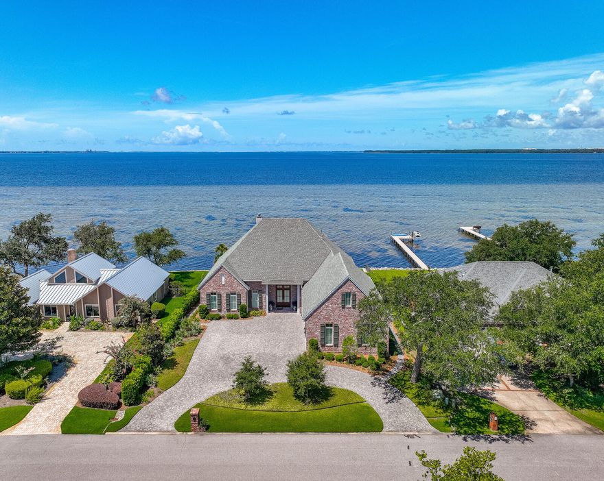 EXQUISITE custom waterfront home built by award winning Key Lime Construction in the gated community of Windward in Bluewater Bay. Enjoy panoramic sunset bay views from almost every room in the home as well as from the pool deck and dock! This 4761sf home features 4 bedrooms and 5.5 baths as well as a heated saltwater pool and a HUGE 3 car garage. When you enter through the large front door you will be captivated by the bay views through the floor to ceiling windows along the back of the house. The living and dining room are open to the kitchen that is defined by gorgeous brick arches. The living room features built in book cases as well as a wonderful wine room with a separate cooling system. The well-appointed kitchen has an abundance of cabinets, beautiful quartz counters and stainless appliances. Just off of the kitchen is a sitting room surrounded by glass that is the perfect place to watch the sun set over the bay. The downstairs master suite offers stunning views of the bay and the master bath with its custom curved shower is sure to pamper you. The 2nd bedroom is also downstairs and it features a private bath making it a perfect guest suite. There is also a convenient office space leading to an oversized laundry room with space for an additional refrigerator and additional storage cabinets. Upstairs you will find a HUGE flex space that is heated and cooled by a ventless HVAC system that can be used as a gym, office, additional bedroom, etc. The two bedrooms upstairs each have a private bath and there is also an additional living area making this upstairs space perfect for extended family. You will LOVE the TWO large storage rooms upstairs as well. Back downstairs, you will find the oversized 3 car garage with a epoxy floor that is cooled by another ventless HVAC system. You will love entertaining and watching dolphins swim by from the large covered back porch overlooking the pool, firepit and dock area. This amazing home will make all your waterfront dreams come true!!