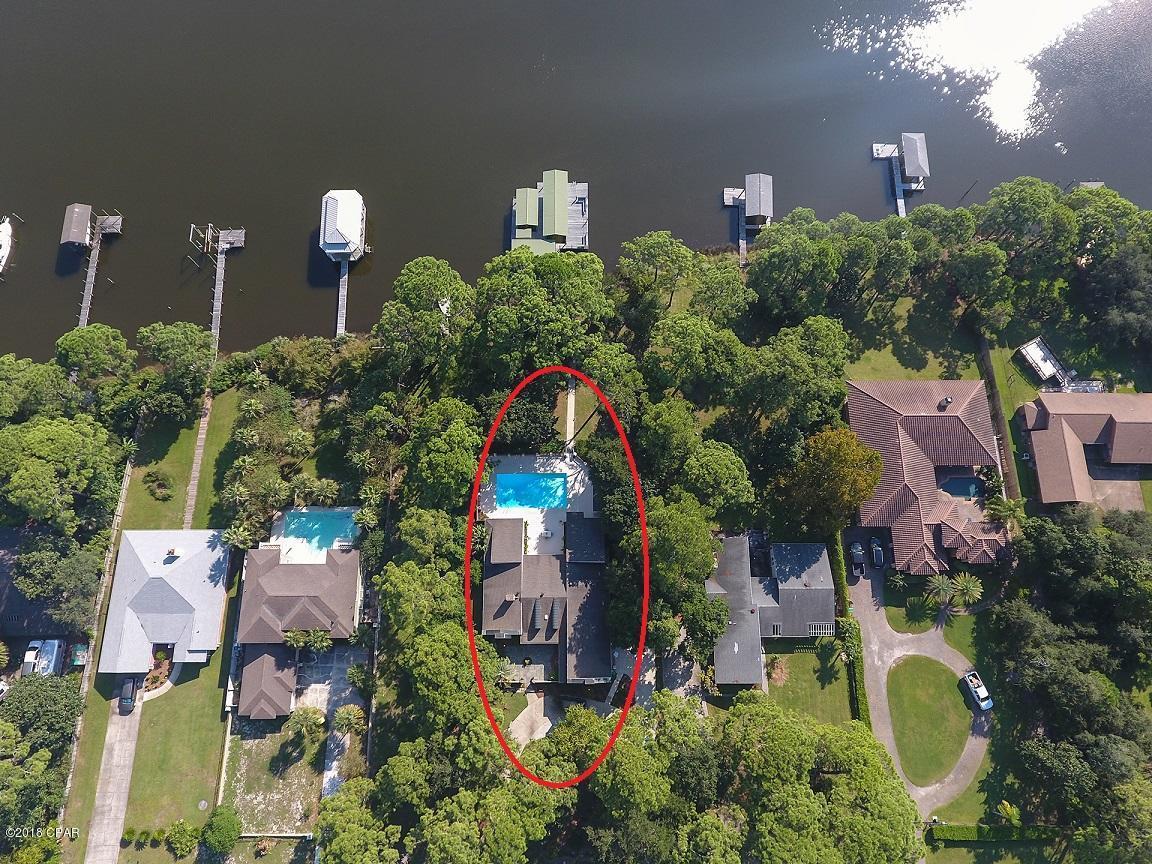 This beautiful waterfront home offers seclusion and privacy in a prime location on Grand Lagoon with 105 feet of water frontage. Enjoy your huge dock with 2 boat slips, a boatlift, and seating area - the perfect place to soak up the serenity of the lagoon. Exterior features include a front yard with a semi-circle drive as well as a 2-car garage and separate parking area. There is a private pool and spacious patio as well as a fenced yard just steps below the pool, and a pathway leading to the dock - the perfect area for kids and pets to play! The spacious open floor plan includes 2 living areas - one includes a wet bar with ice maker. The front living room and dining room are separated by a double-sided wood burning fireplace.