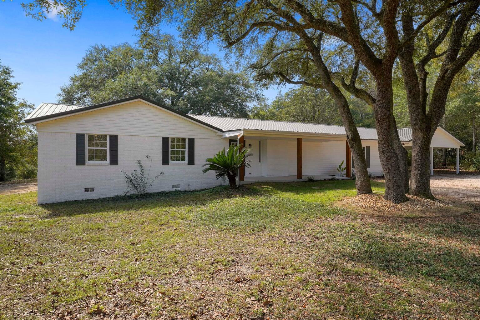 Located on a peaceful 4.05-acre lot, this charming 4-bedroom, 2-bathroom farmhouse offers over 2,400 sq ft of living space. Featuring a spacious Florida room, updated kitchen and bathrooms, and recent improvements including a new HVAC system (2022), septic tank (2022), and water heater (2020). The property is surrounded by natural beauty with walnut trees, grapevines, and blueberry bushes. Additional storage shed and covered area for chickens. Conveniently located with easy access to military bases, schools, shopping, and just 45 minutes from Destin's beaches. A perfect blend of country living and modern convenience.