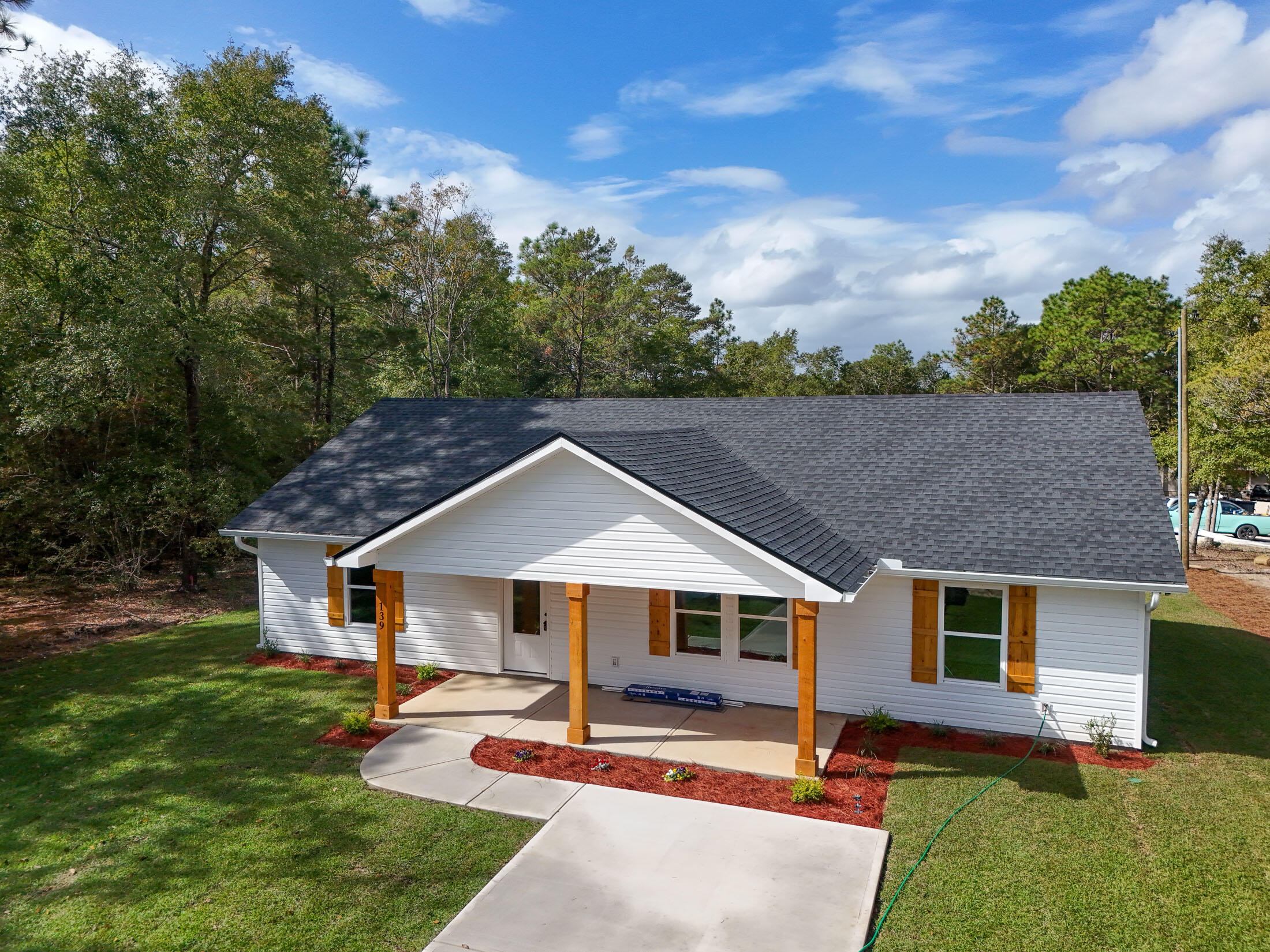 Situated on a corner lot just outside of town, this stunning new home by Darby Homes perfectly blends modern design with timeless charm. The inviting front porch, accented with charming cypress posts, welcomes you into a bright, open-concept space with vaulted ceilings. The kitchen is a chef's dream, boasting quartz countertops, soft-close shaker cabinets, a stainless farmhouse sink, and stainless steel appliances. The east-facing primary suite, filled with natural light, features a walk-in closet and an ensuite bathroom with double vanities, quartz countertops, and a custom-tiled shower. Two guest bedrooms are thoughtfully positioned on the opposite side of the home for privacy. A spacious back porch completes the home, offering an ideal space to relax or entertain.