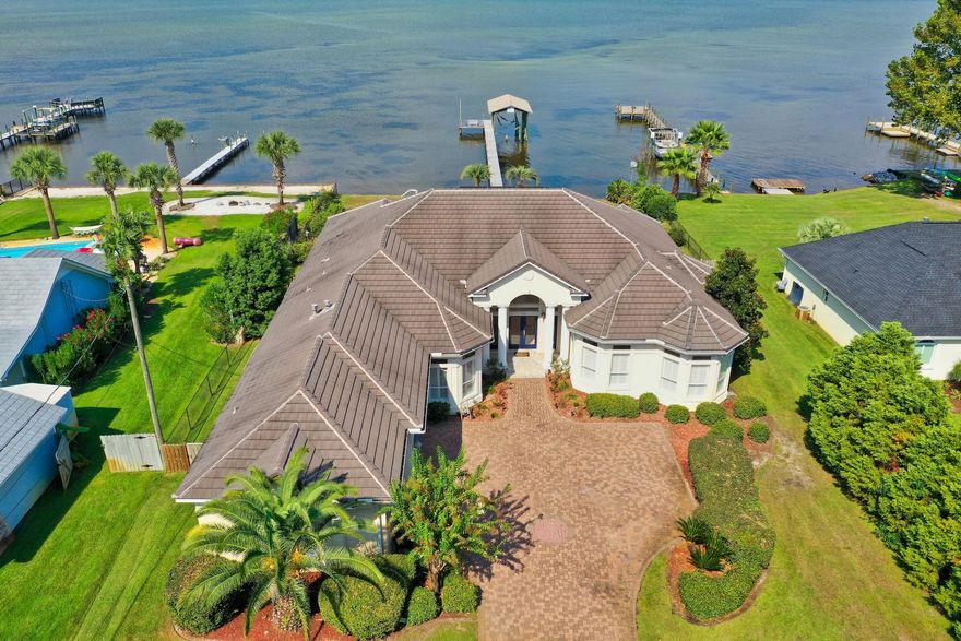 Enjoy coastal living in a serene tropical setting with this Bay front estate in Miramar Beach! This home is on an expansive and private lot boasting over 1/2 an acre. With 100 ft of water frontage on the Bay, you have your own private oasis! Home is complete with dock, boathouse with slip, sun deck, incredible screened-in pool and covered lanai. Outdoor features a huge back yard with tropical landscaping setting this home apart from the rest. *Check out the lifestyle video and virtual tour of this amazing property in the Photos section.* Ideally the home is one level with beautiful architectural details like trayed ceilings, stunning archways, crown molding & lots of windows offering great natural light and panoramic views of the Bay. The interior has been repainted for a fresh look